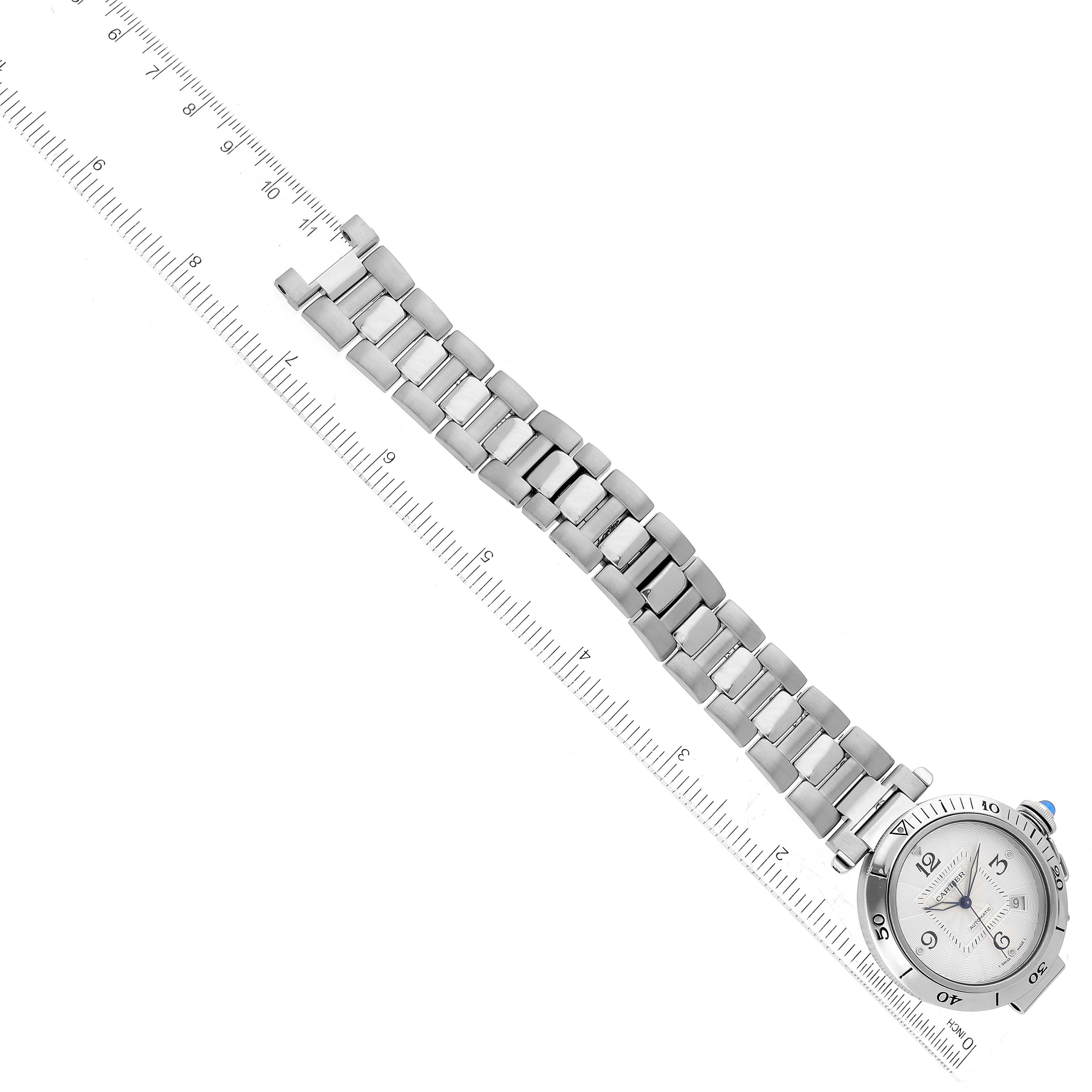 This image shows a top view of a Cartier Pasha W31059H3 Men
s Stainless Steel Silver Dial W31059H3 Men
s Stainless Steel Silver Dial watch with its face and metal bracelet aligned next to a ruler for size reference.