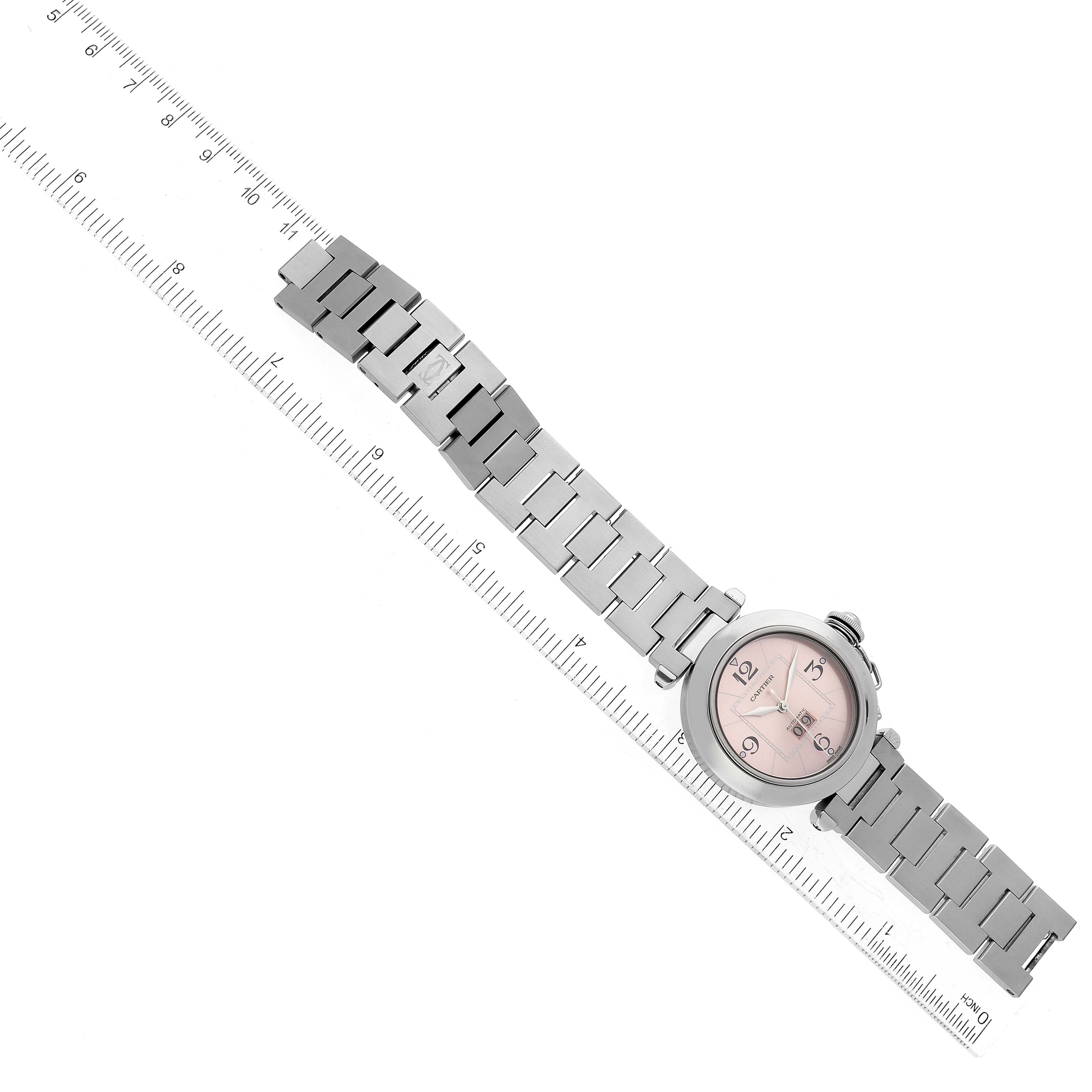 The image shows an overhead view of a Cartier Pasha W31058M7 Women's Stainless Steel Pink Dial W31058M7 Women's Stainless Steel Pink Dial watch with a ruler for scale.