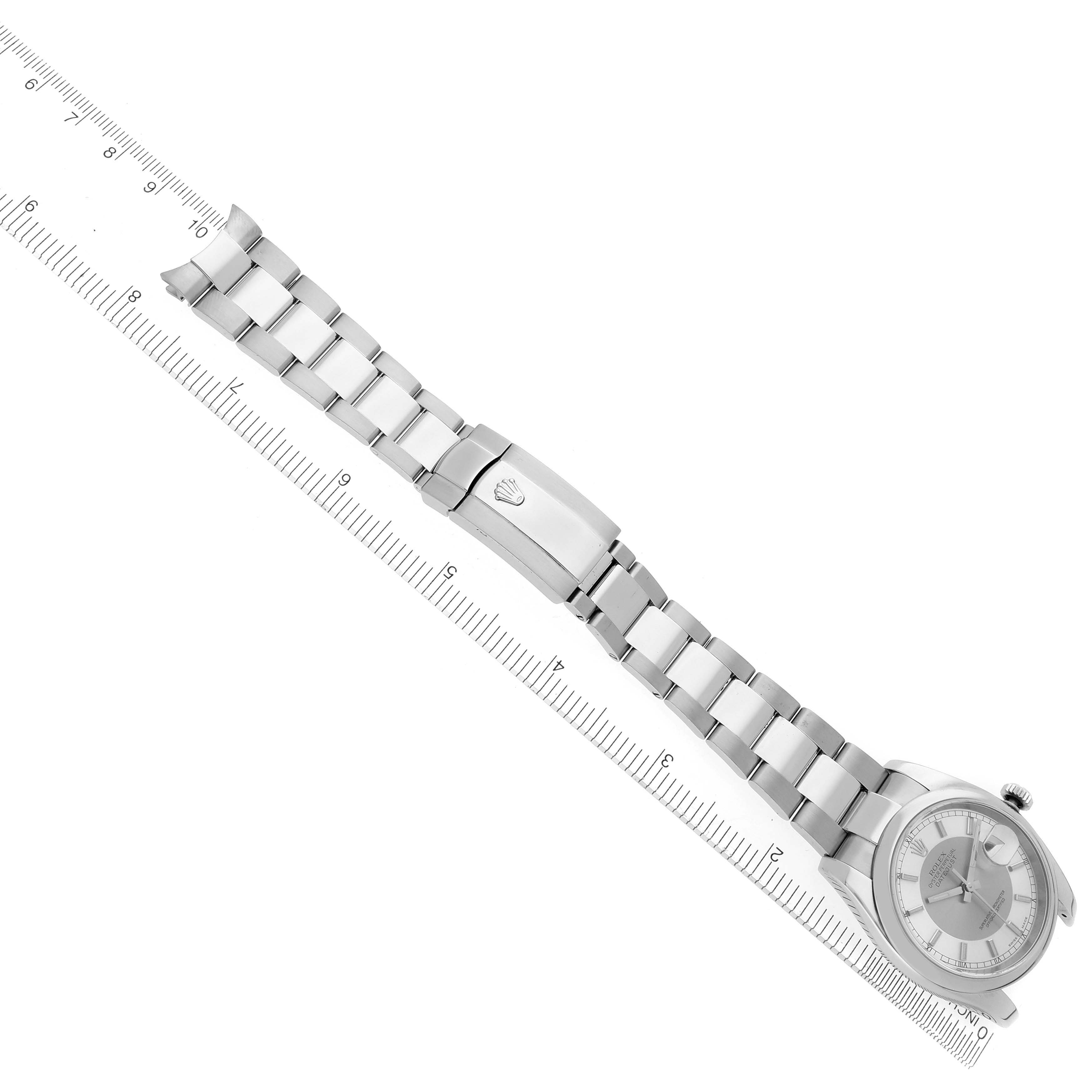 The Rolex Datejust 116200 Men's Stainless Steel Silver Dial 116200 Men's Stainless Steel Silver Dial watch is shown from above, highlighting the watch face, bracelet, and clasp, aligned next to a ruler.