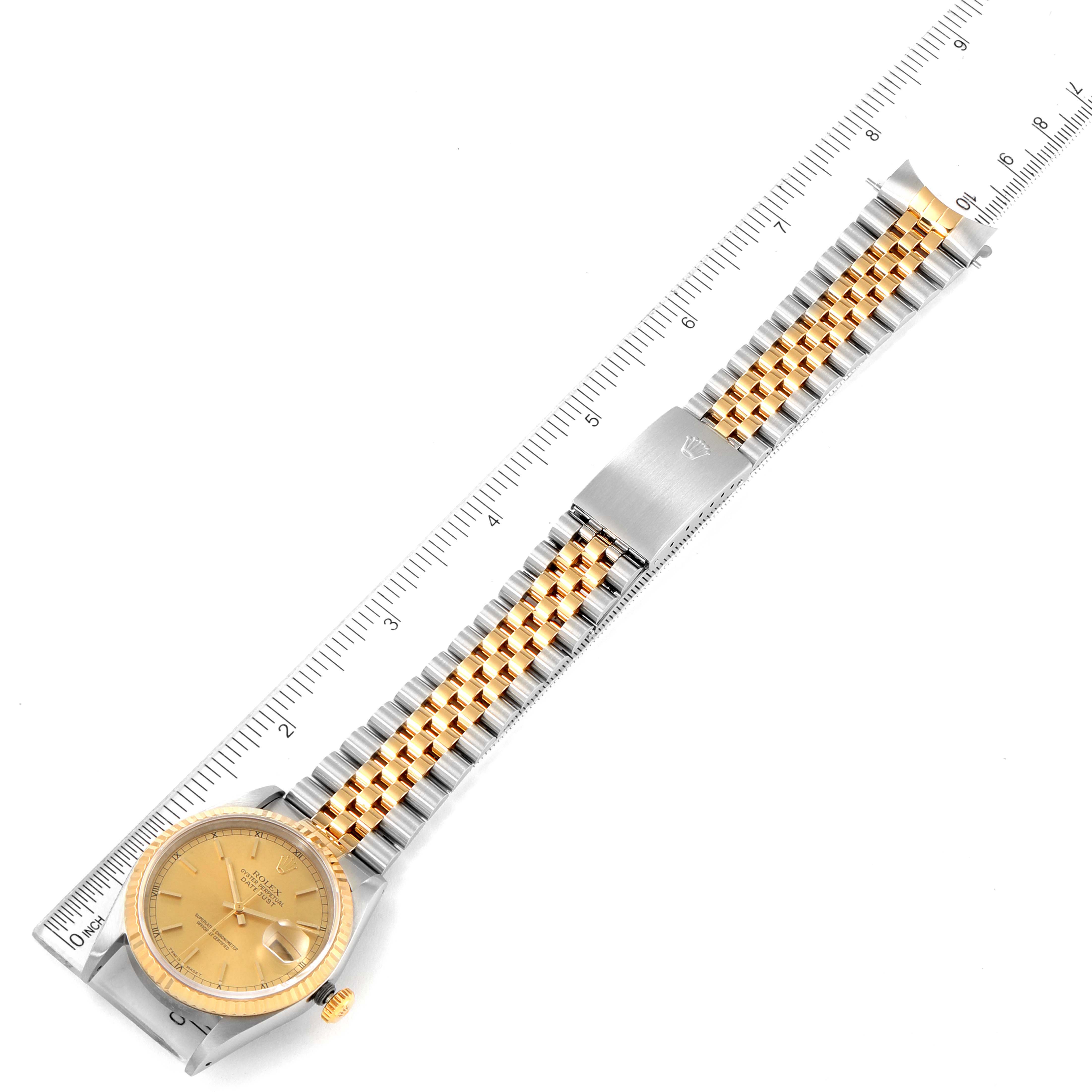 This image shows the Rolex Datejust 16233 Men
s Steel and Gold (two tone) Champagne Dial 16233 Men
s Steel and Gold (two tone) Champagne Dial watch laid flat, featuring its face, bracelet, and a ruler for scale.