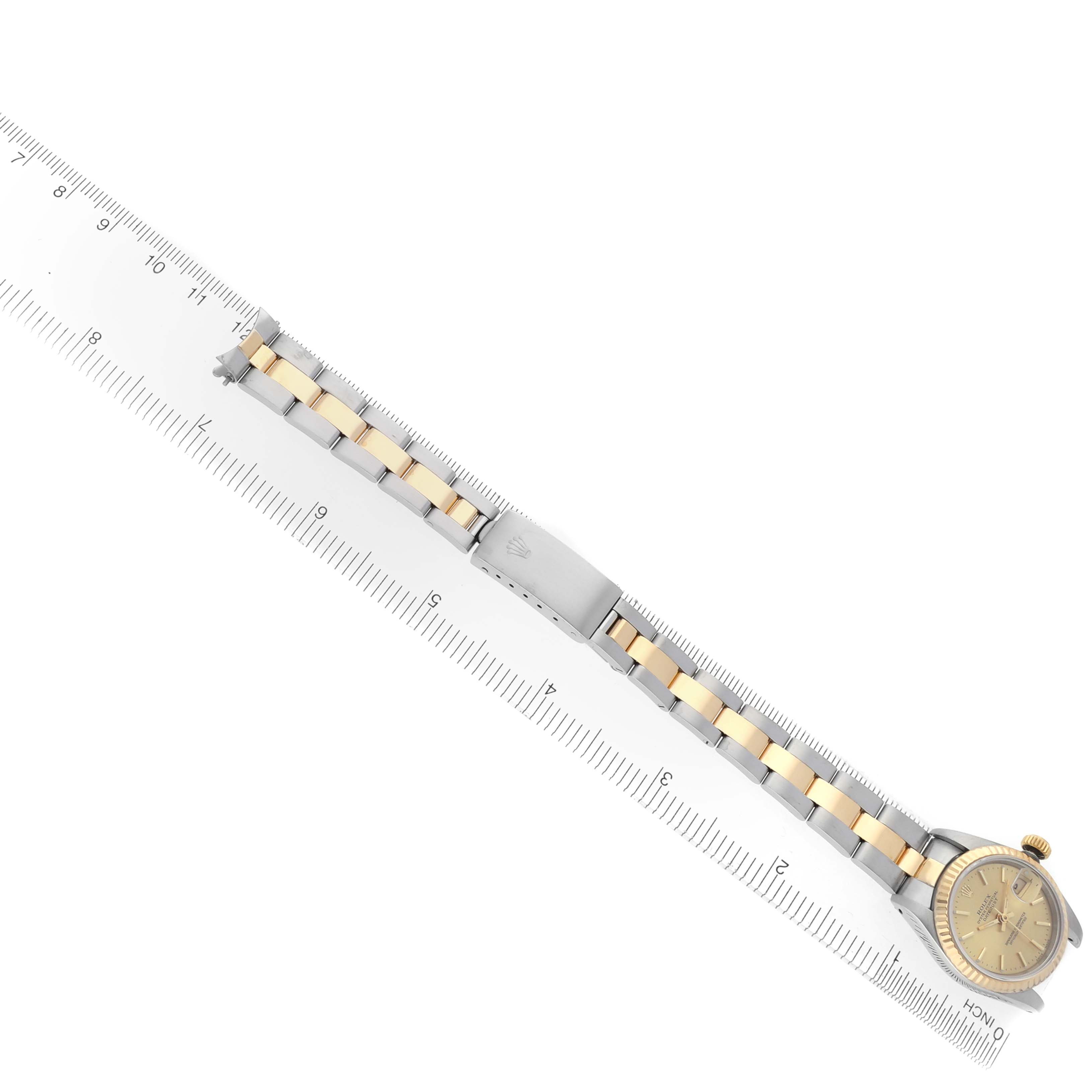 The Rolex Datejust 69173 Women's Steel and Gold (two tone) Champagne Dial 69173 Women's Steel and Gold (two tone) Champagne Dial watch is shown from a top-down angle, displaying the bracelet and clasp alongside a ruler for scale.