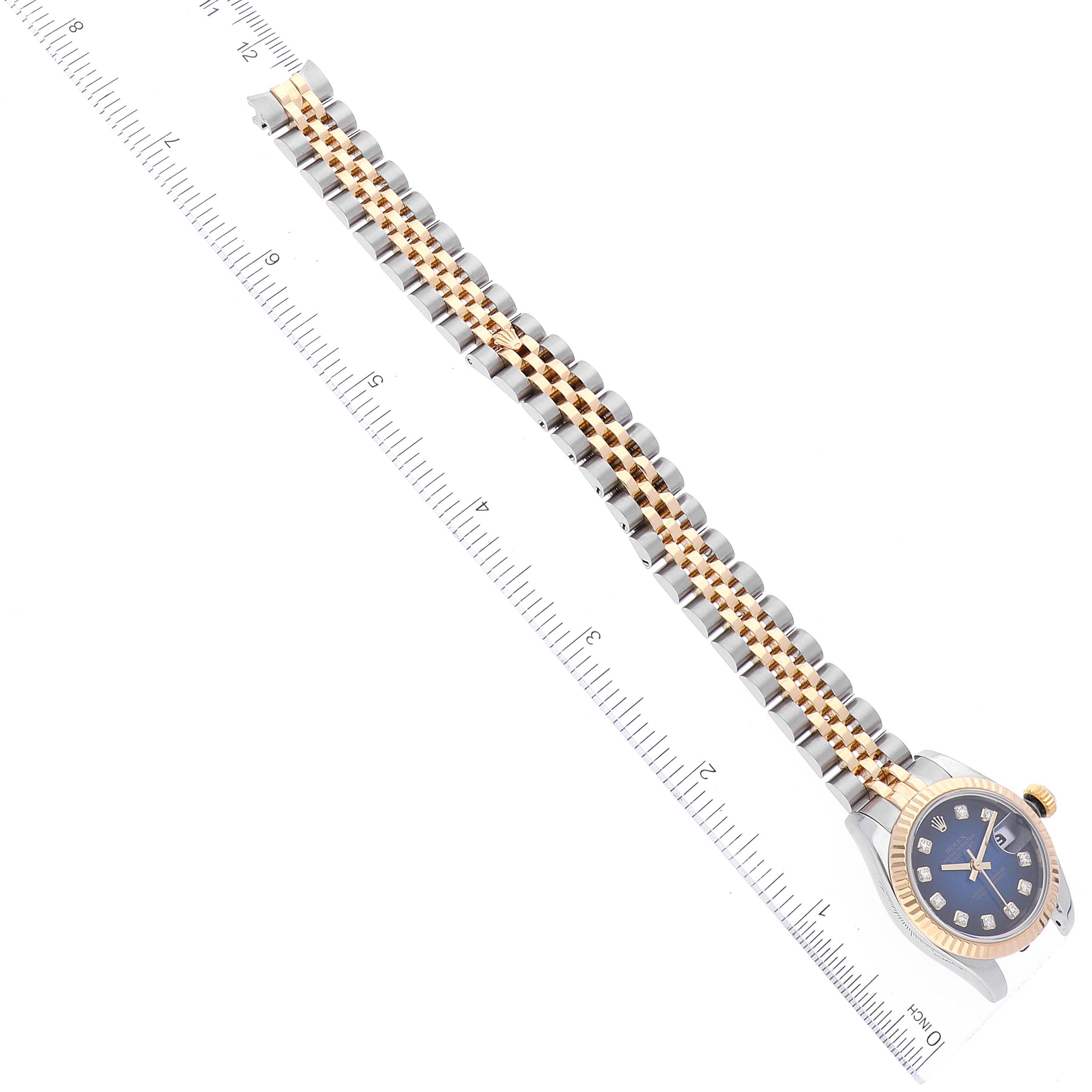 The image shows a Rolex Datejust 179173 Women's Steel and Gold (two tone) Blue Dial 179173 Women's Steel and Gold (two tone) Blue Dial watch laid flat with its bracelet fully extended alongside a ruler.
