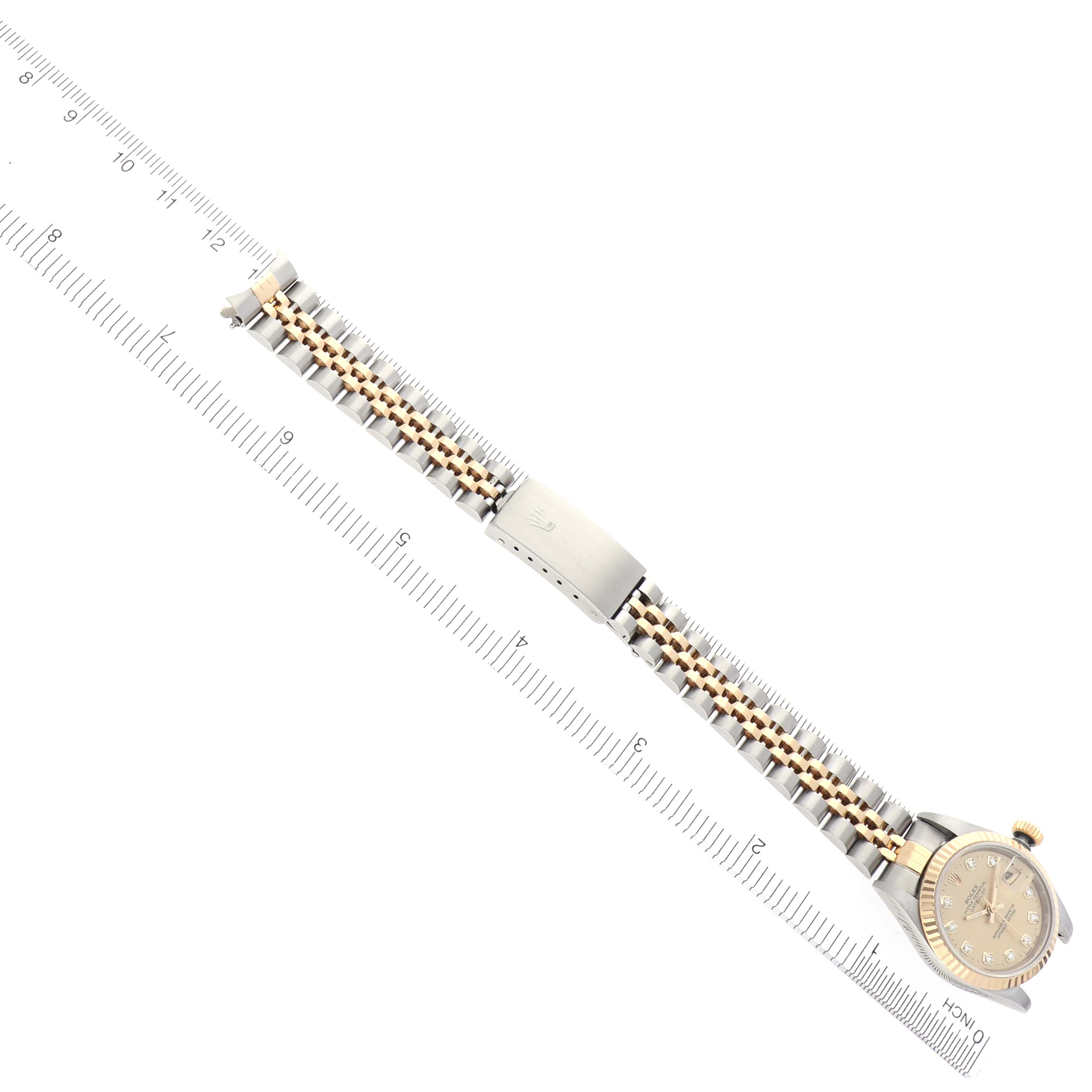 The image shows a top-down view of a Rolex Datejust 69173 Women's Steel and Gold (two tone) Champagne Dial 69173 Women's Steel and Gold (two tone) Champagne Dial watch, displaying its bracelet and watch face next to a ruler.