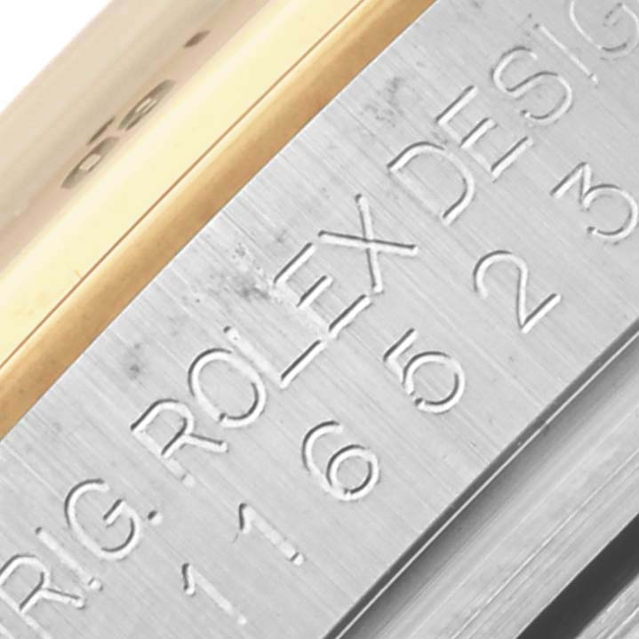 The image shows a close-up of the engraved side of the Rolex Daytona 116523 Men
s Steel and Gold (two tone) Black Dial 116523 Men
s Steel and Gold (two tone) Black Dial, displaying the model and the brand name.