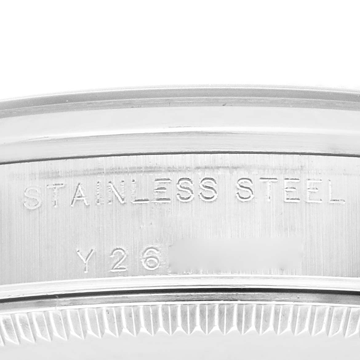 This close-up image shows the engraved stainless steel bezel of a mid-size Rolex watch, focusing on the serial number area.