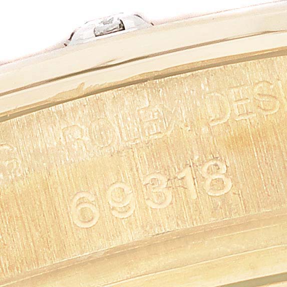 The image shows a close-up of the Rolex Pearlmaster 69318 Women's Yellow Gold Silver Dial 69318 Women's Yellow Gold Silver Dial's case edge displaying engraved text and the model number.