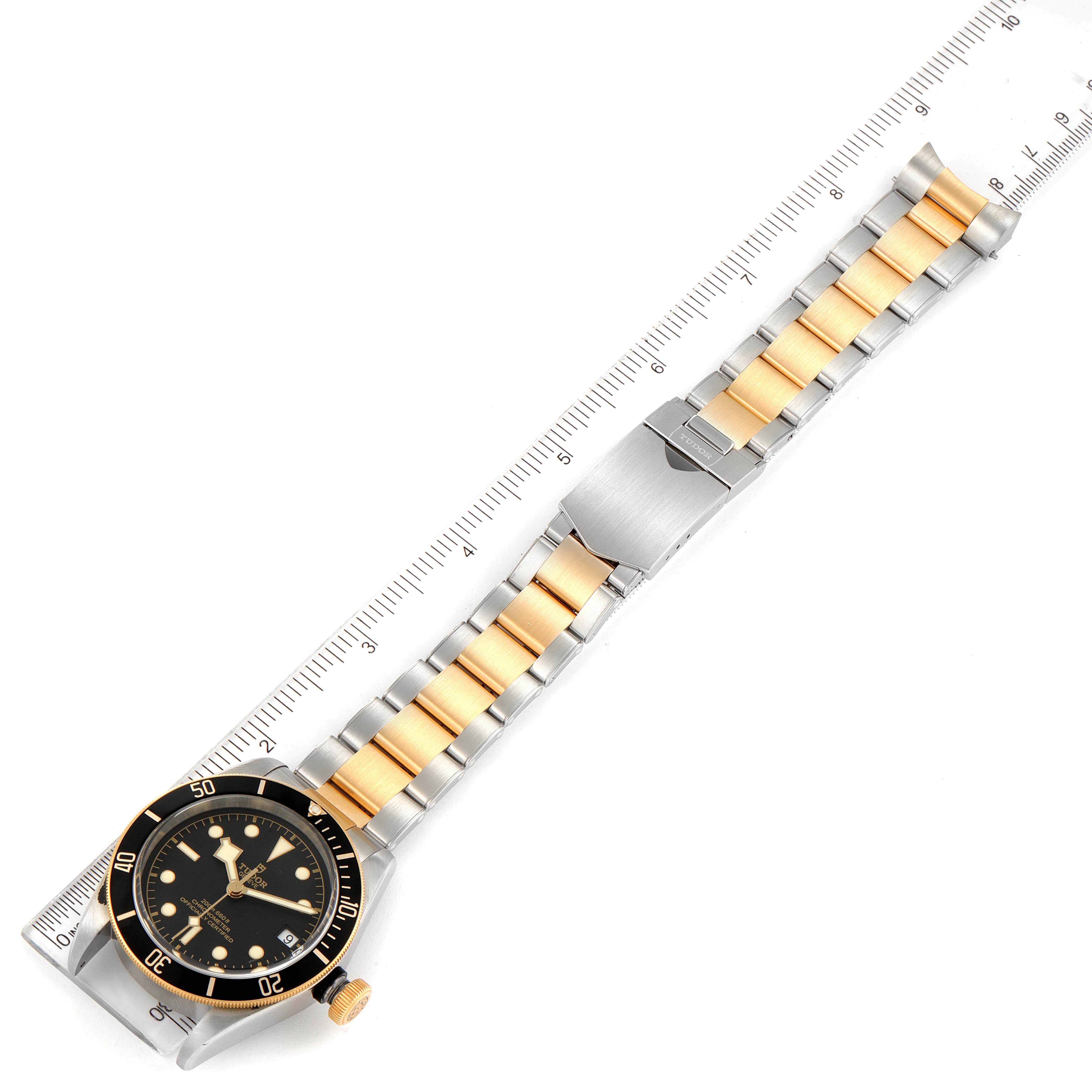 The Tudor Heritage Black Bay 79733 Men's Steel and Gold (two tone) Black Dial 79733 Men's Steel and Gold (two tone) Black Dial watch is shown from a top view, with a focus on the bezel, dial, bracelet, and clasp.