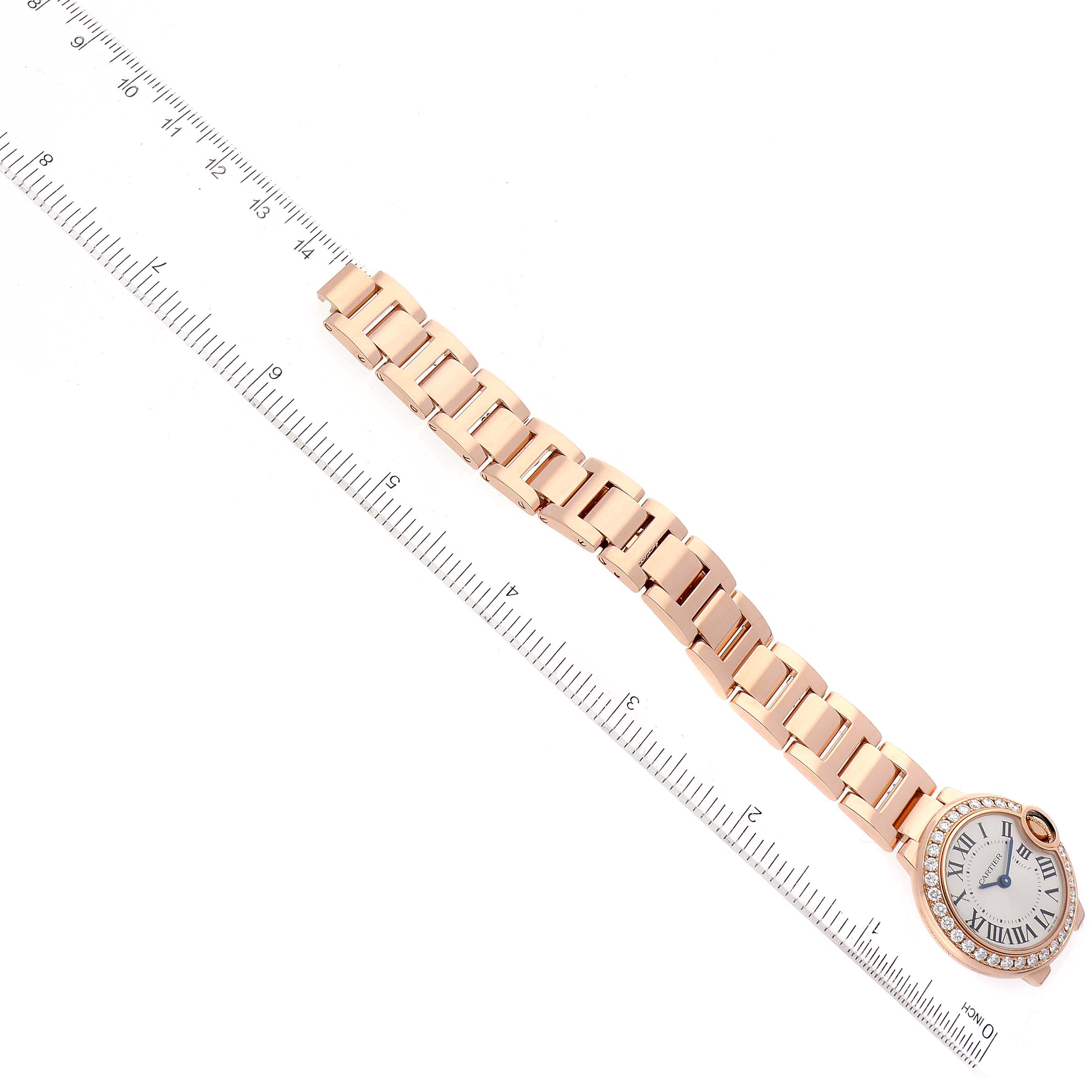 This image shows a Cartier Ballon Bleu WJBB0015 Women
s Rose Gold Silver Dial WJBB0015 Women
s Rose Gold Silver Dial watch laid flat with a rose gold bracelet next to a ruler for size reference.