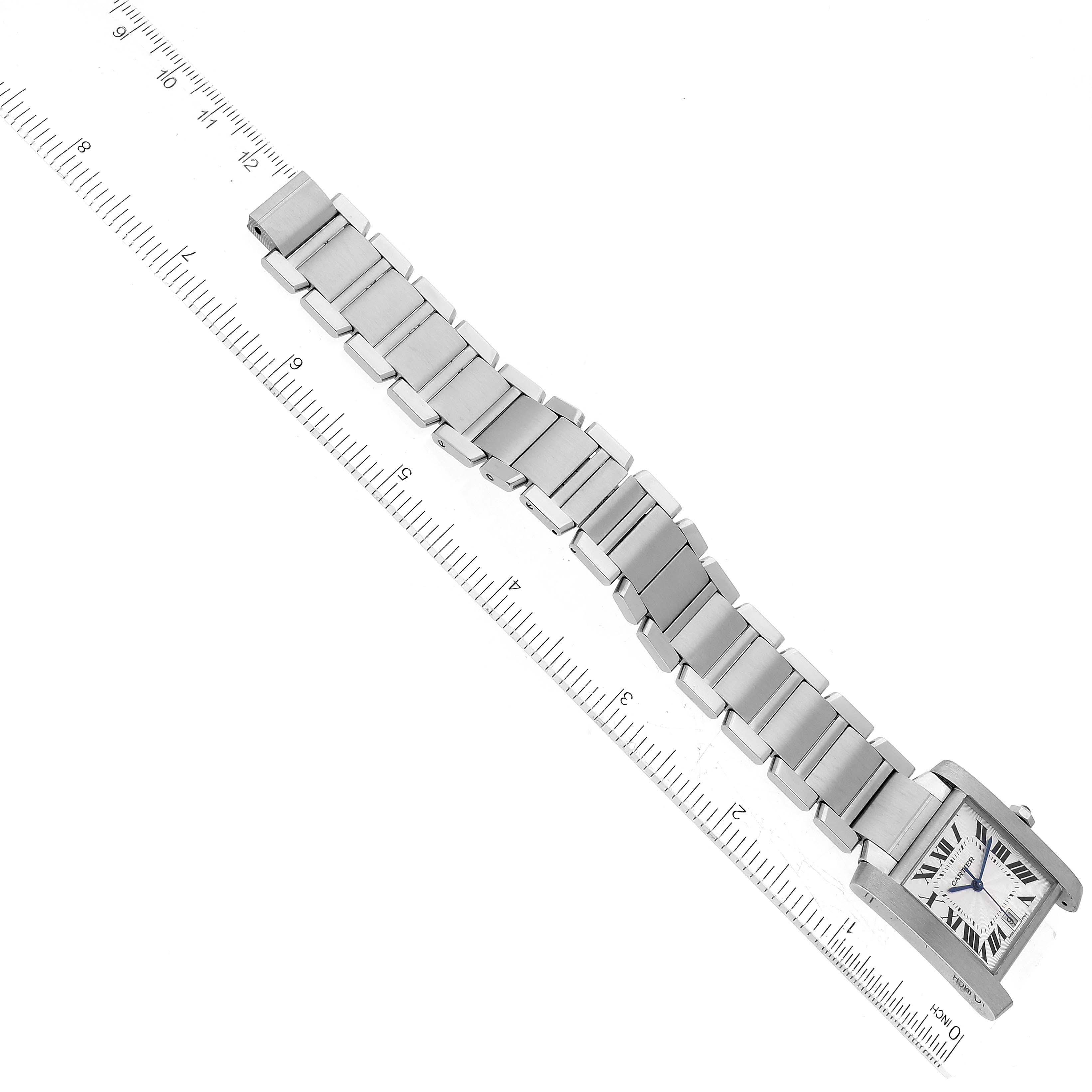 The image shows an overhead view of a Cartier Tank Francaise W51002Q3 Men
s Stainless Steel Silver Dial W51002Q3 Men
s Stainless Steel Silver Dial watch, featuring the face and metal strap next to a ruler.