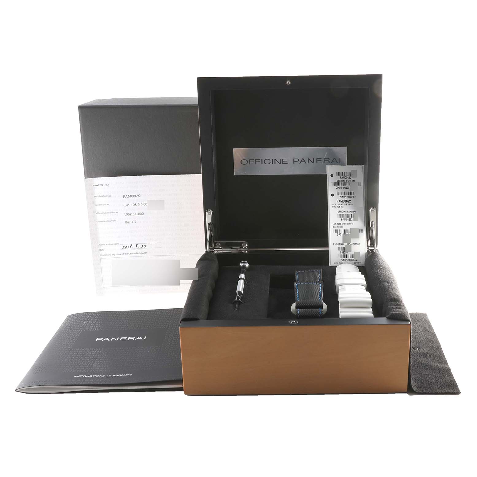 The image shows a Panerai Submersible PAM00692 Men's Titanium Blue Dial PAM00692 Men's Titanium Blue Dial watch box with accessories including straps and a tool, viewed from the top.