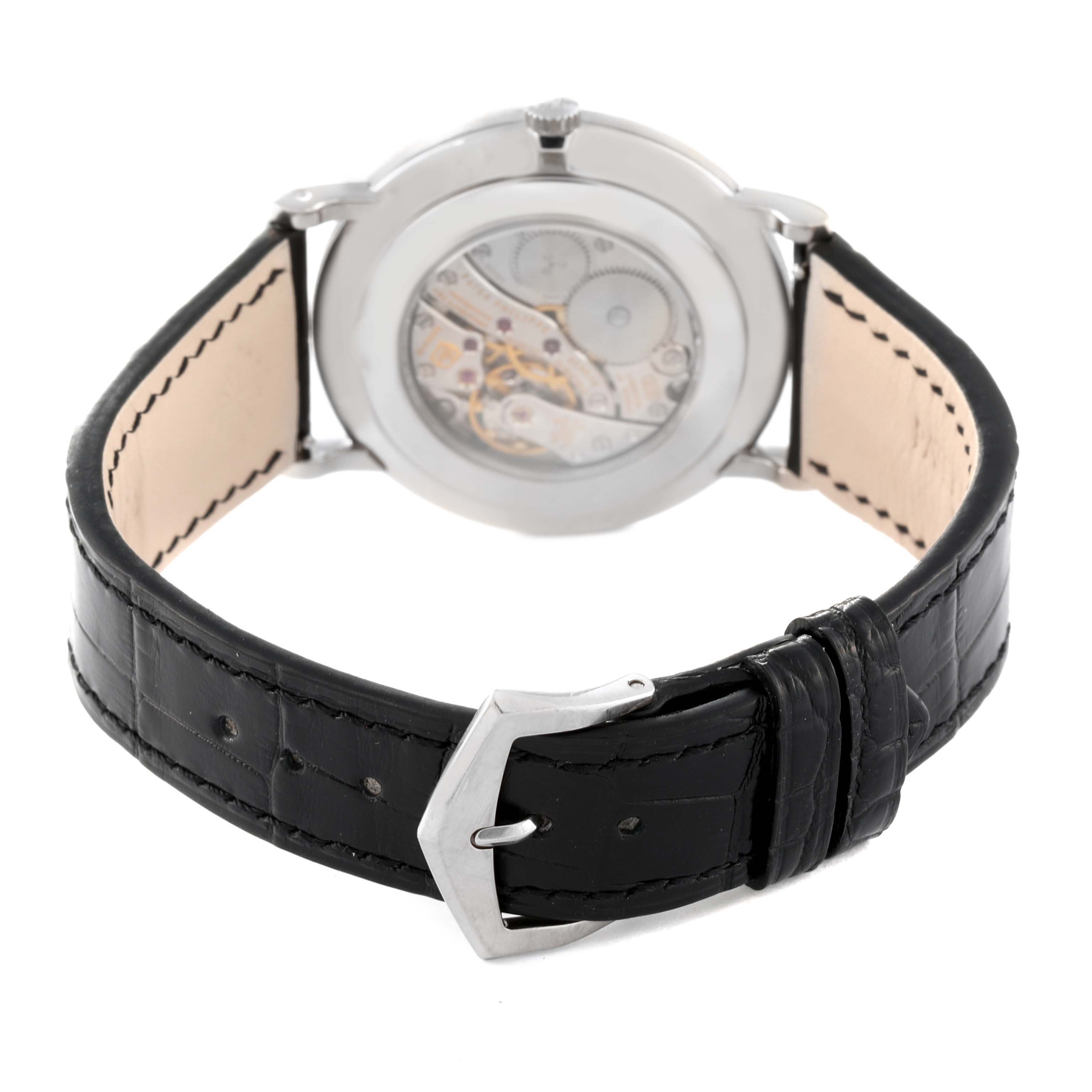 The image shows the backside and open mechanism of a Patek Philippe Calatrava 5116G Men
s White Gold White Dial 5116G Men
s White Gold White Dial watch with a black leather strap and a buckle.