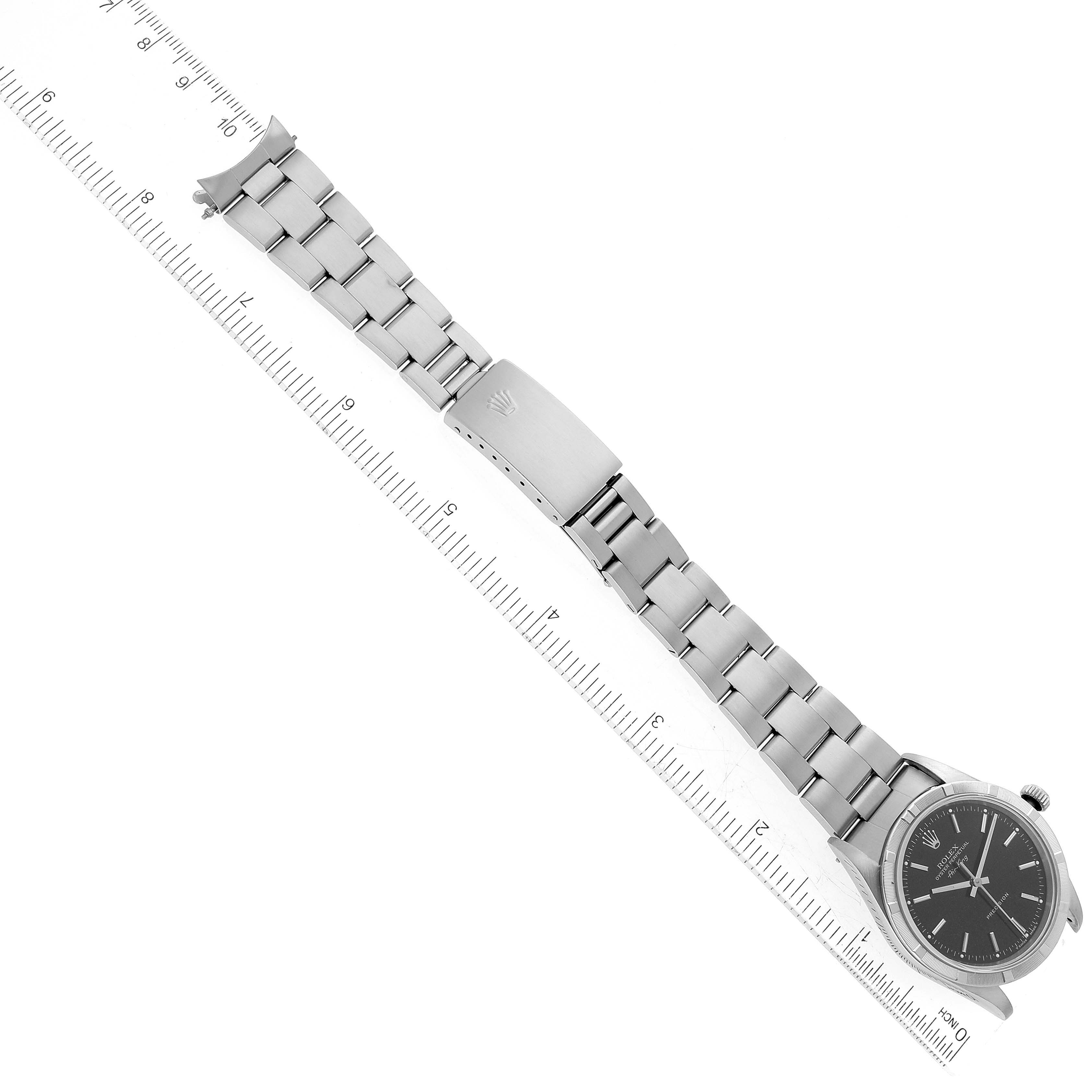 This image shows a top-down view of a Rolex Air-King 14010 Men's Stainless Steel Black Dial 14010 Men's Stainless Steel Black Dial watch displaying the face, bracelet, and clasp next to a ruler.
