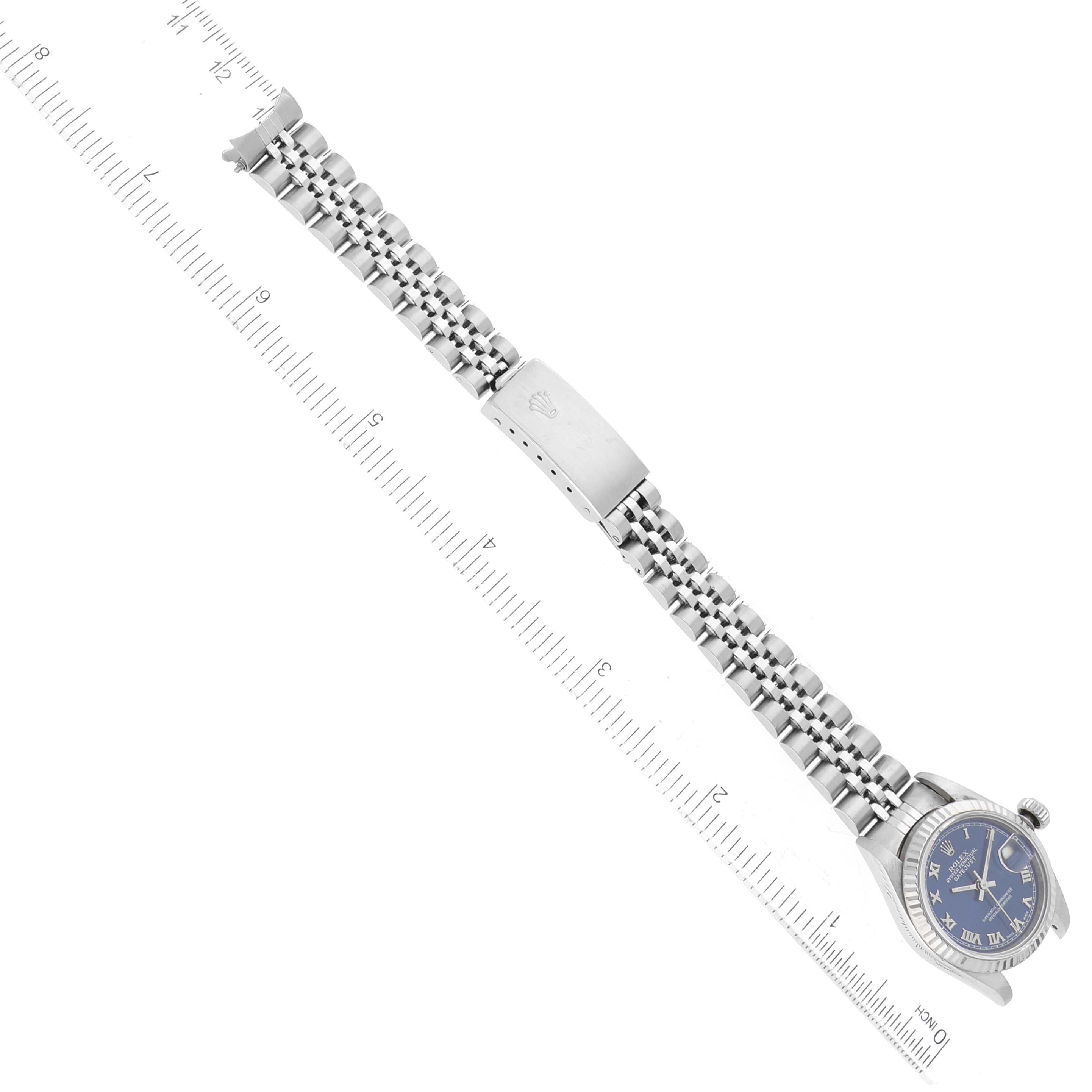 This image shows a Rolex Datejust 79174 Women's Stainless Steel Blue Dial 79174 Women's Stainless Steel Blue Dial watch laid flat with its face, band, and clasp visible, alongside a ruler for scale.