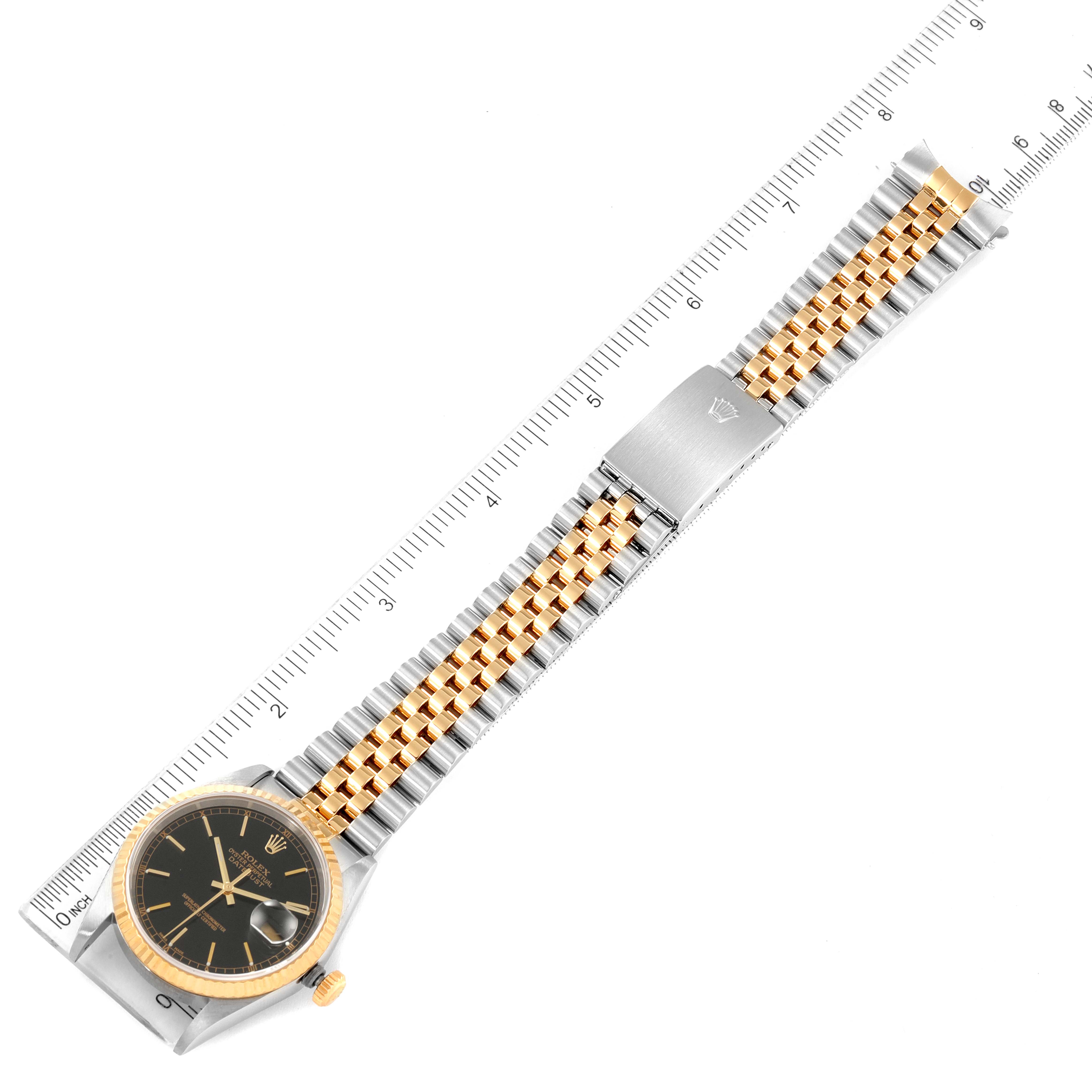 The Rolex Datejust 16233 Men's Steel and Gold (two tone) Black Dial 16233 Men's Steel and Gold (two tone) Black Dial watch is shown flat with a ruler measuring the length of its metal bracelet and clasp.
