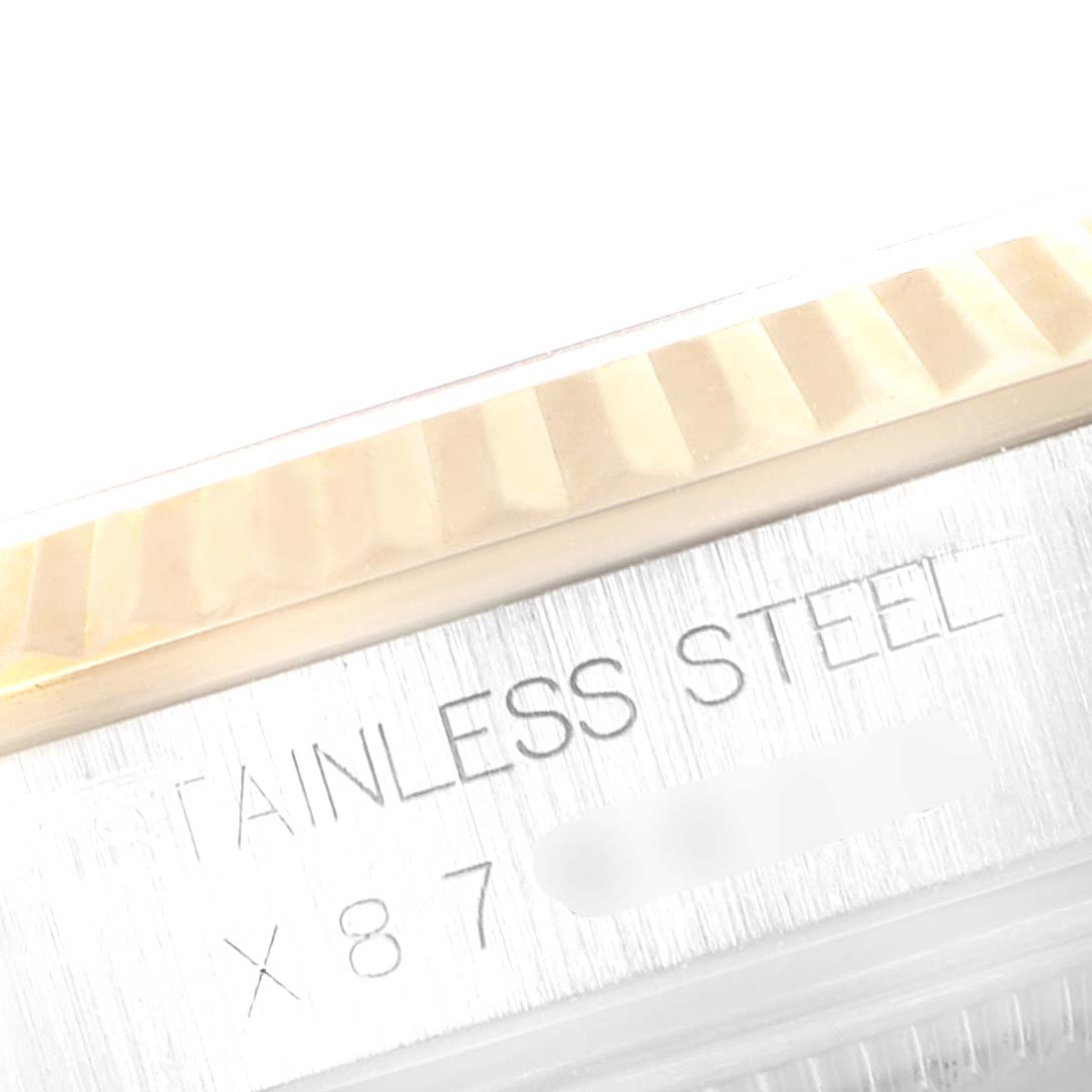 This close-up image of a Rolex Datejust 16233 Men's Steel and Gold (two tone) Champagne Dial 16233 Men's Steel and Gold (two tone) Champagne Dial watch shows part of the case with engraving, near the fluted bezel.