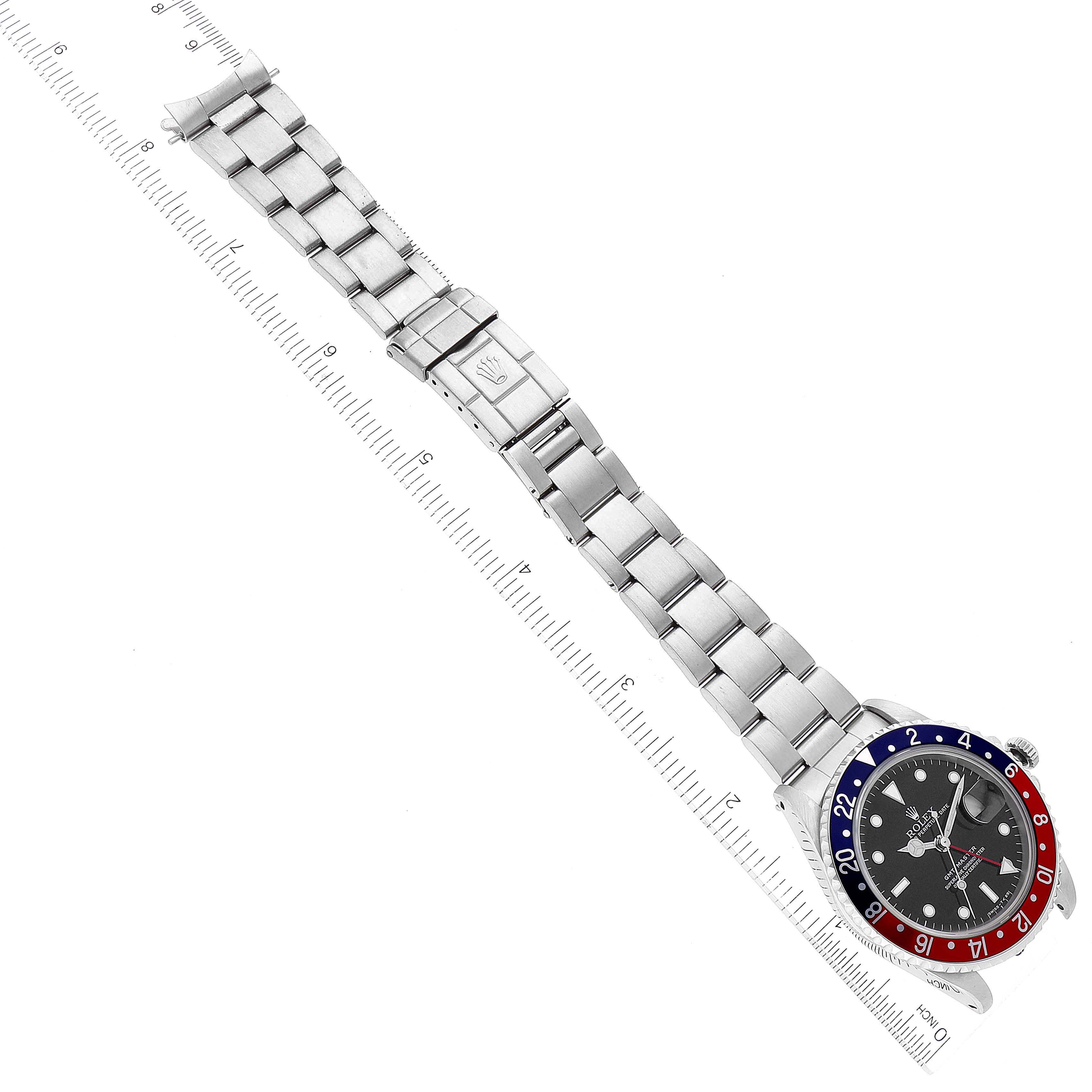 The image shows a top-down view of a Rolex GMT-Master 16700 Men's Stainless Steel Black Dial 16700 Men's Stainless Steel Black Dial watch, highlighting the bezel, dial, and bracelet placed next to a ruler.