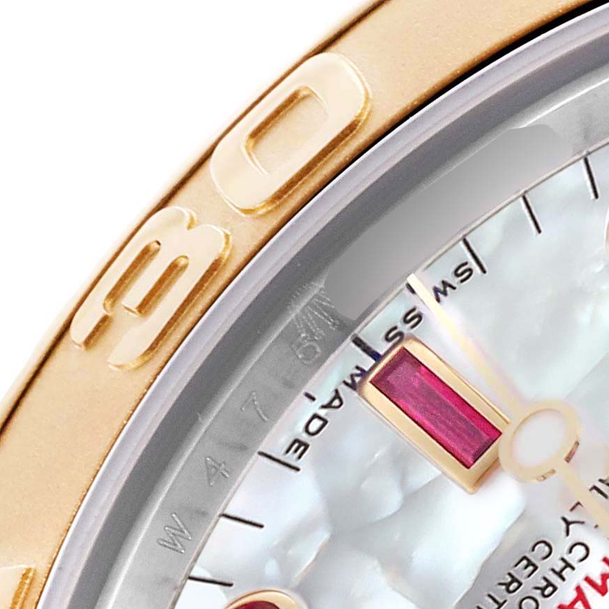 The image shows a close-up of the bezel and part of the dial of a Rolex Yacht-Master 168623 Men's Steel and Gold (two tone) Mother of Pearl Dial 168623 Men's Steel and Gold (two tone) Mother of Pearl Dial, highlighting the gold markings and ruby hour marker.