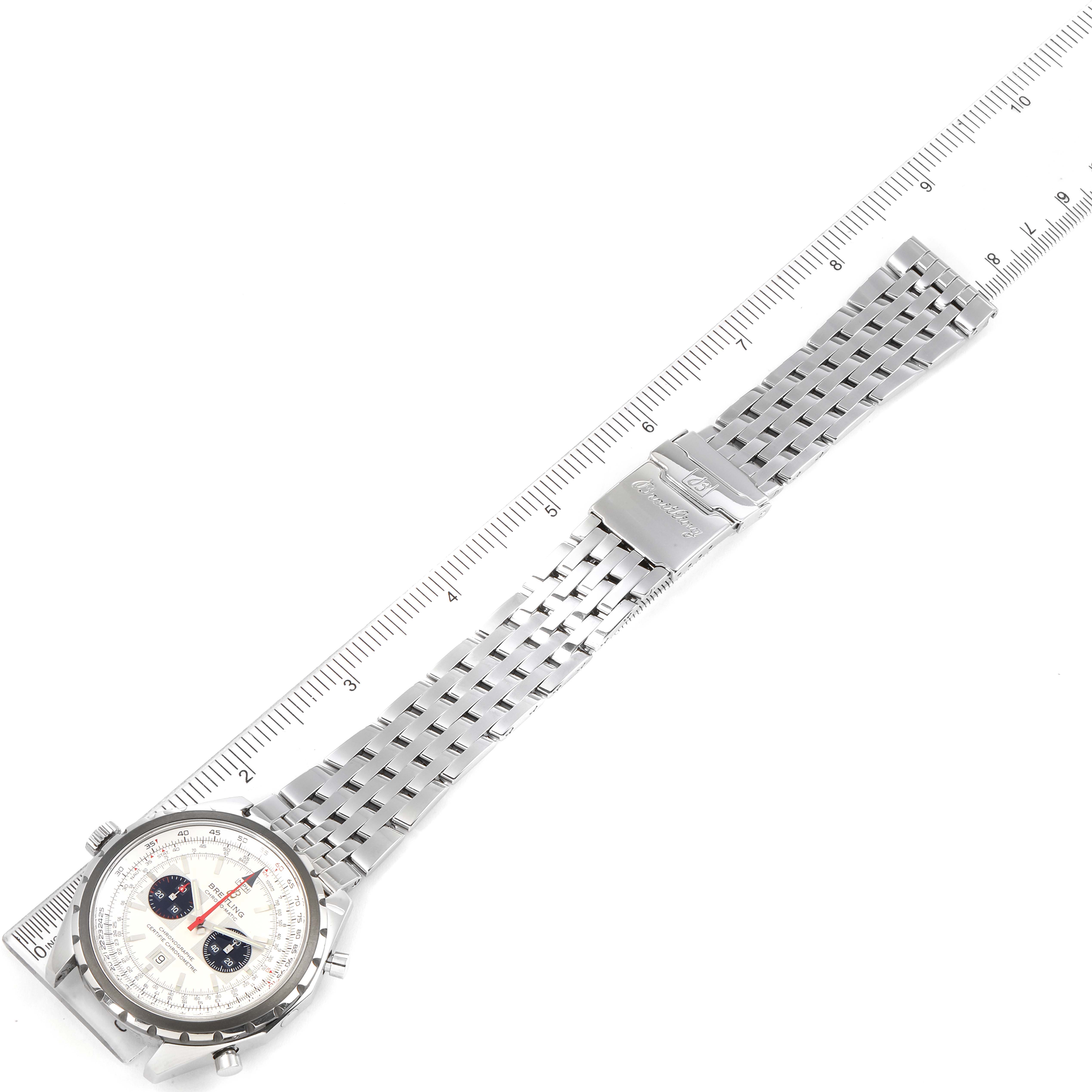 The image shows the Breitling Chronomatic A41360 Men's Stainless Steel Silver Dial A41360 Men's Stainless Steel Silver Dial watch laid flat alongside a ruler, displaying the face, bezel, and metal bracelet.