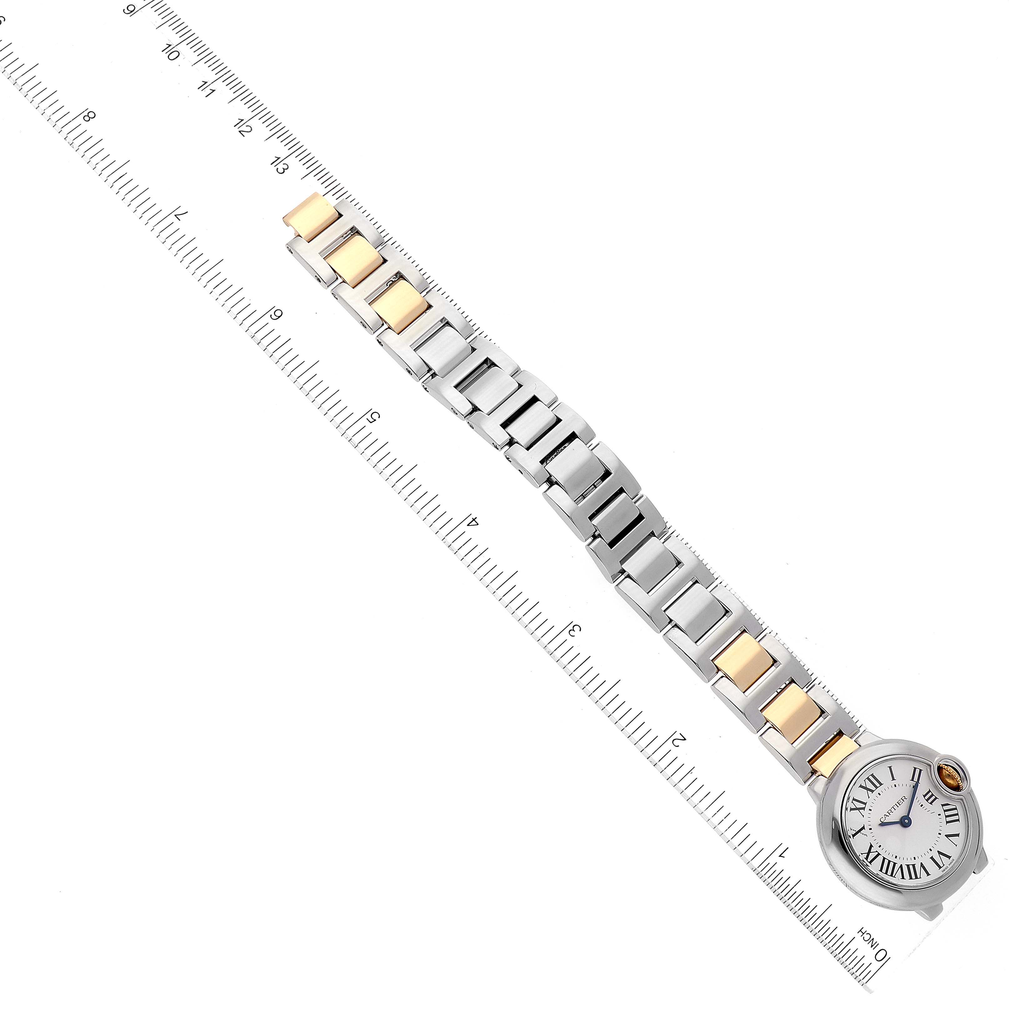 The image shows an overhead view of a Cartier Ballon Bleu W69007Z3 Women
s Steel and Gold (two tone) Silver Dial W69007Z3 Women
s Steel and Gold (two tone) Silver Dial watch with a mixed metal bracelet laid next to a ruler.
