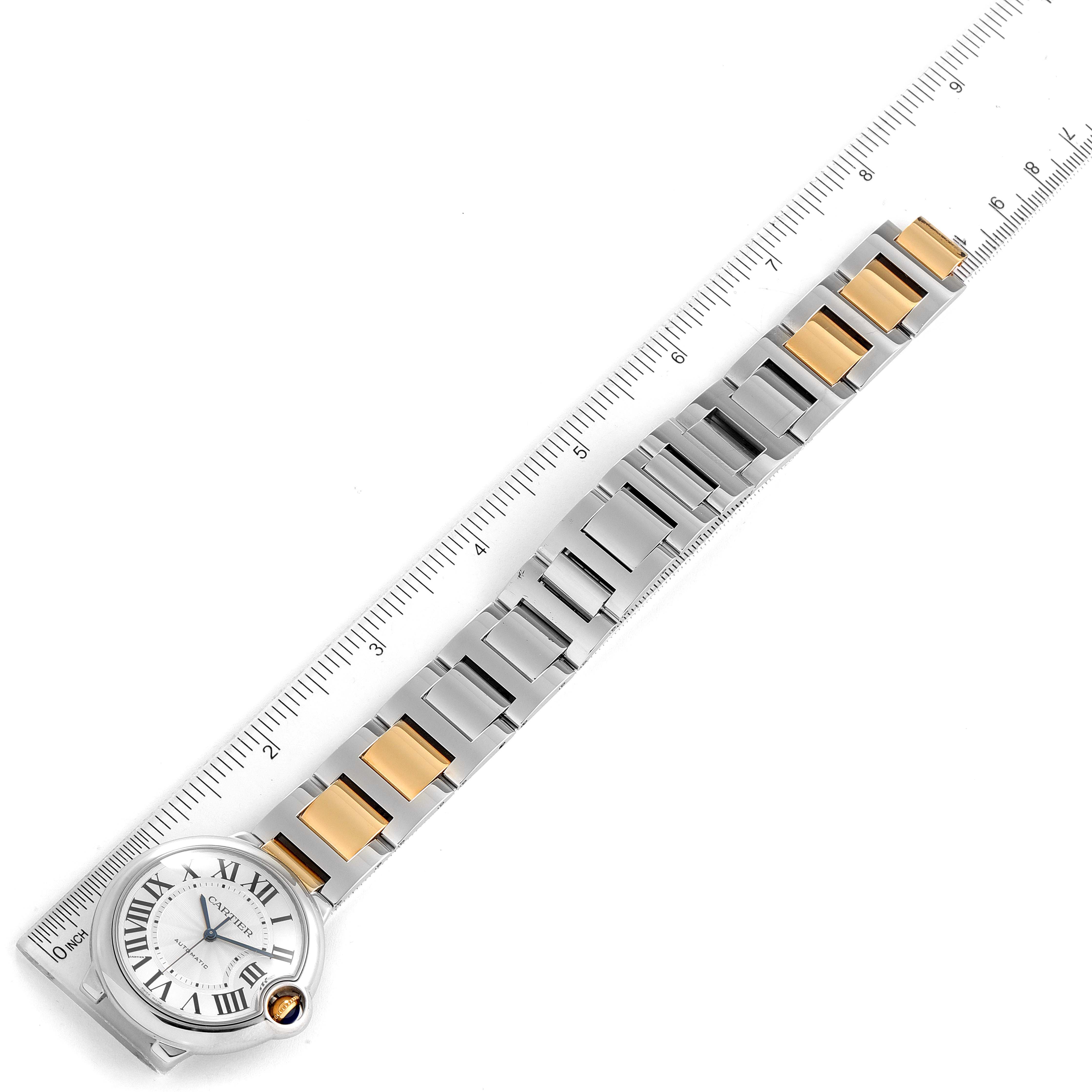 The image shows a Cartier Ballon Bleu W2BB0012 Men's Steel and Gold (two tone) Silver Dial W2BB0012 Men's Steel and Gold (two tone) Silver Dial watch lying flat next to a ruler, highlighting its stainless steel and gold bracelet.