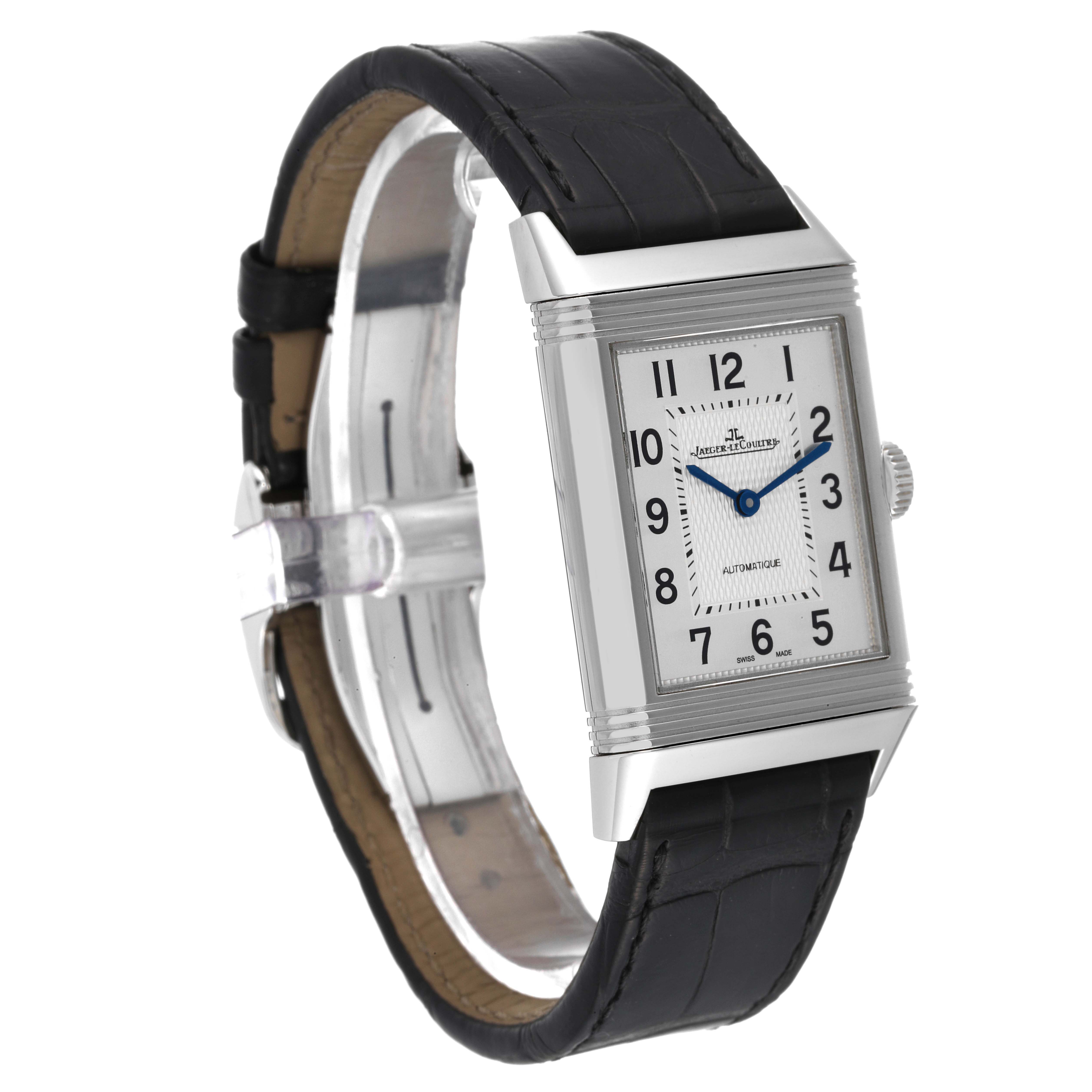 The Jaeger-LeCoultre Reverso watch is shown at a three-quarter angle, highlighting the rectangular dial and black leather strap.