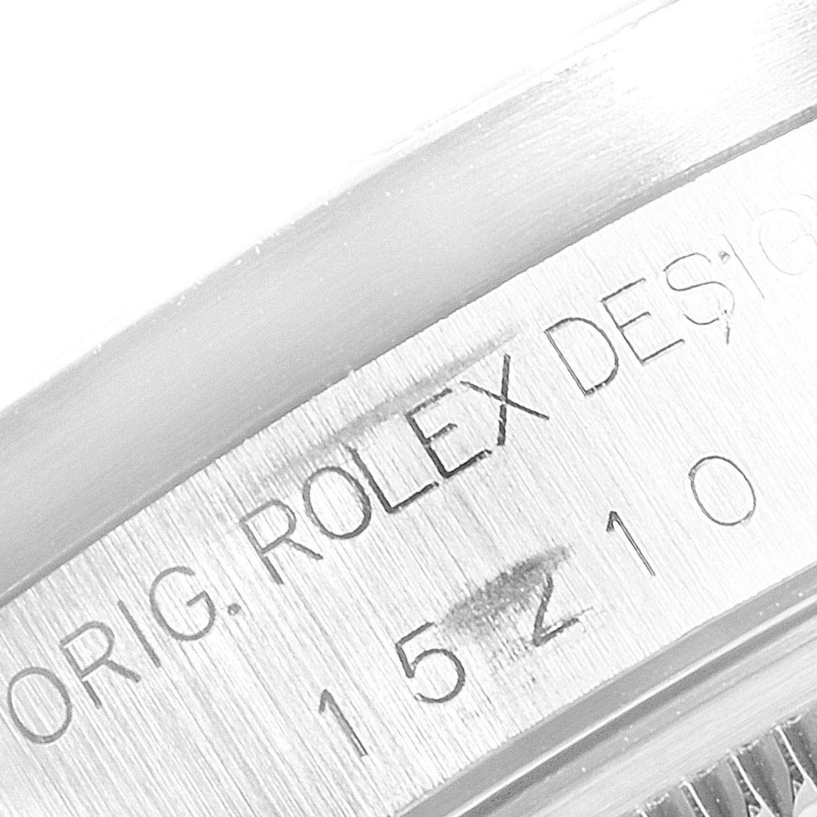 This image shows a close-up of the engraved edge of a Rolex Date 15210 Men's Stainless Steel Black Dial 15210 Men's Stainless Steel Black Dial model watch, featuring part of the serial number and "ROLEX DESIGN".