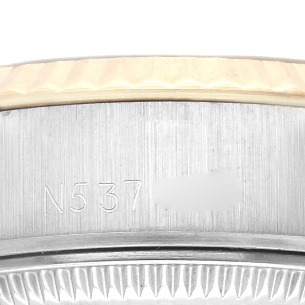 This close-up image of a Rolex Datejust 69173G Women's Steel and Gold (two tone) Champagne Dial 69173G Women's Steel and Gold (two tone) Champagne Dial watch shows part of the bezel and the engraved serial number on the side.