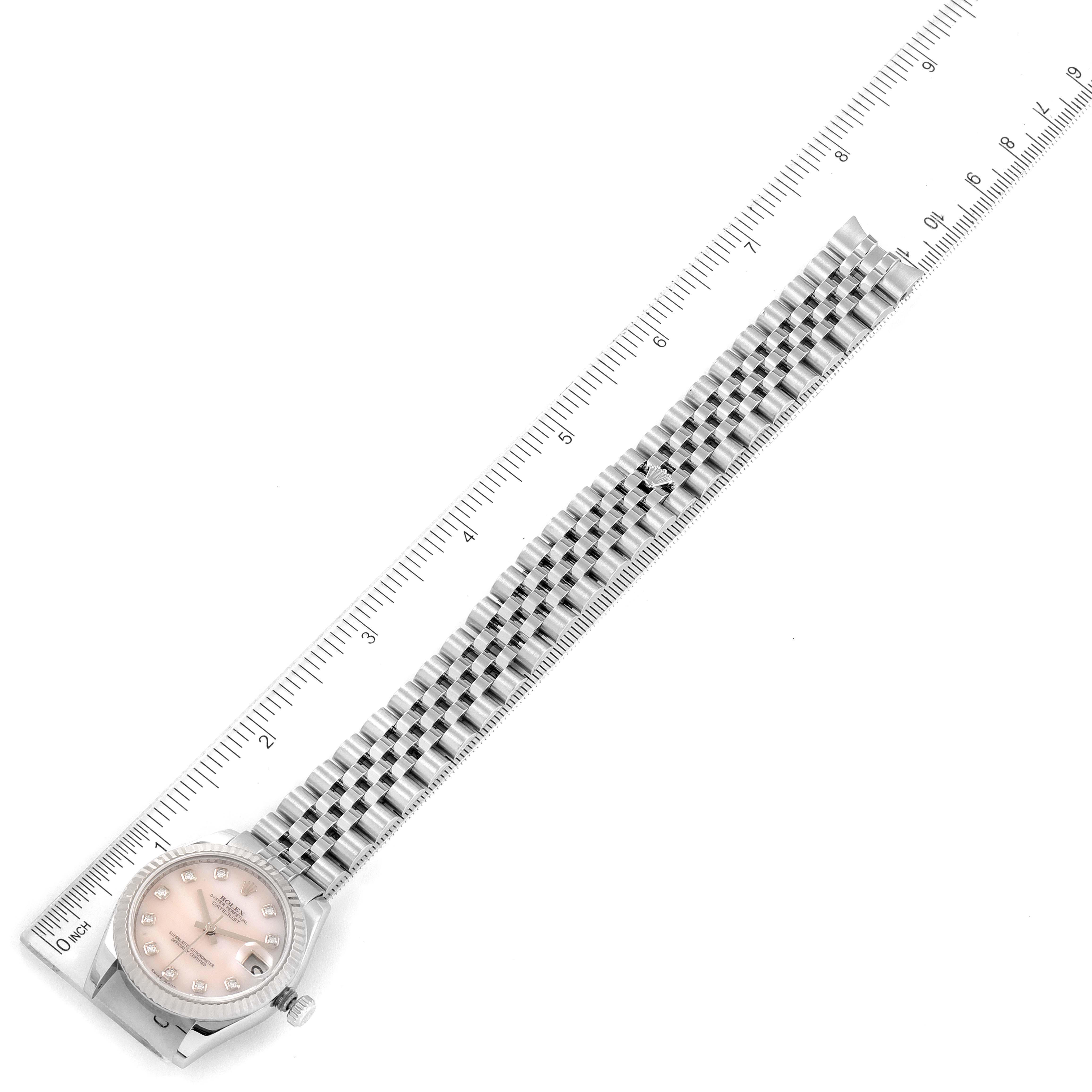The image shows a Mid-Size Rolex watch from a top angle, including the watch face and the entirety of the metal bracelet, with a ruler beside it.