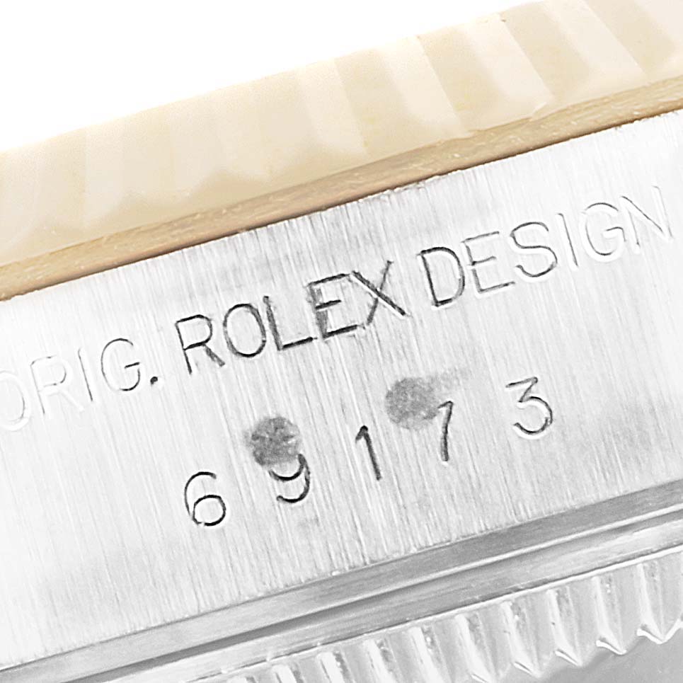 The image shows a close-up of the serial number and "ROLEX DESIGN" engraving on the side case of a Rolex Datejust 69173 Women's Steel and Gold (two tone) Black Dial 69173 Women's Steel and Gold (two tone) Black Dial watch.