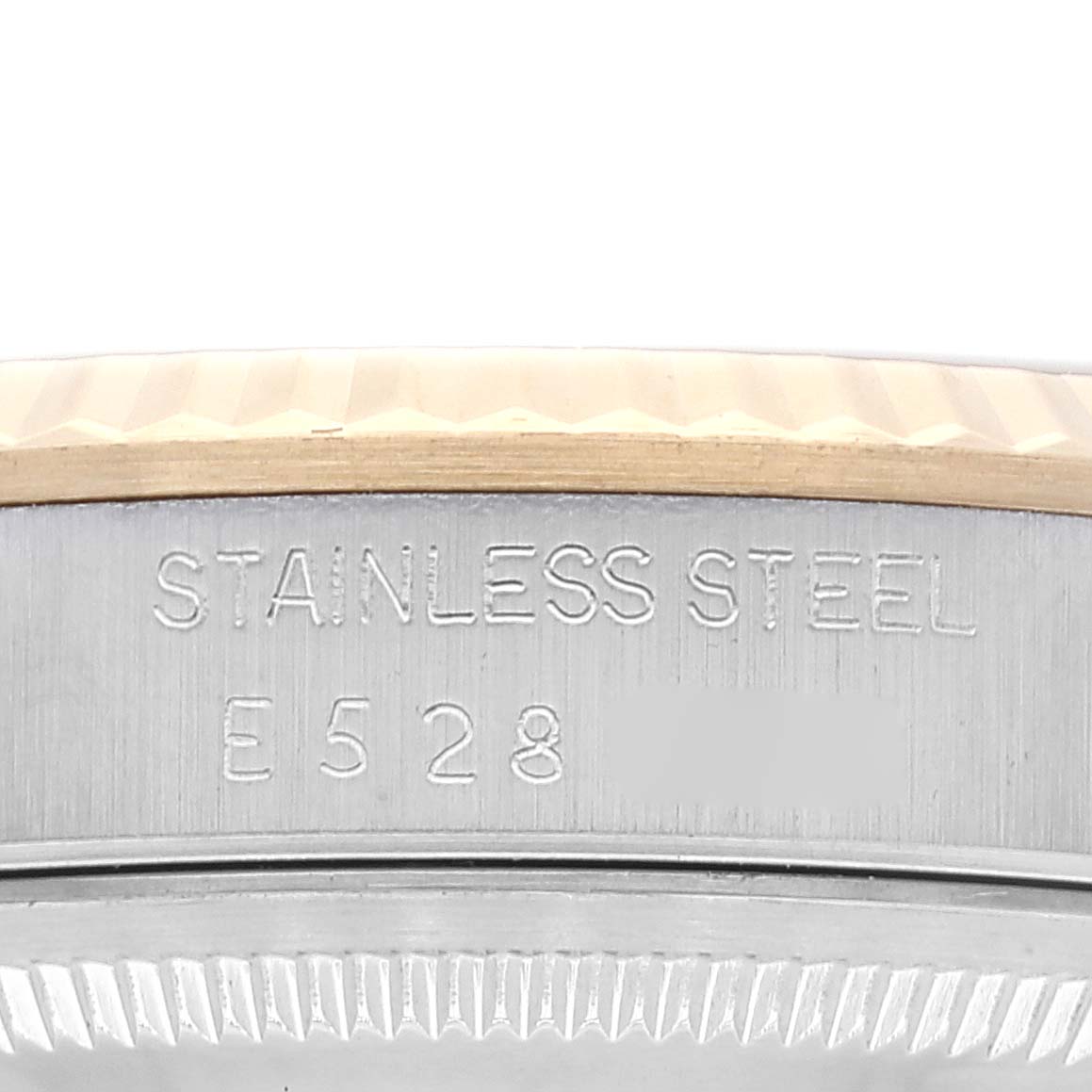 The image shows a close-up of the case side of a Rolex Datejust 16233 Men's Steel and Gold (two tone) Champagne Dial 16233 Men's Steel and Gold (two tone) Champagne Dial watch, highlighting the stainless steel label and a part of the fluted bezel.