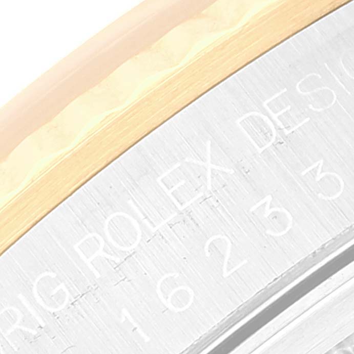 The image shows a close-up of the side engraving and fluted bezel of a Rolex Datejust 16233 Men's Steel and Gold (two tone) Silver Dial 16233 Men's Steel and Gold (two tone) Silver Dial watch.