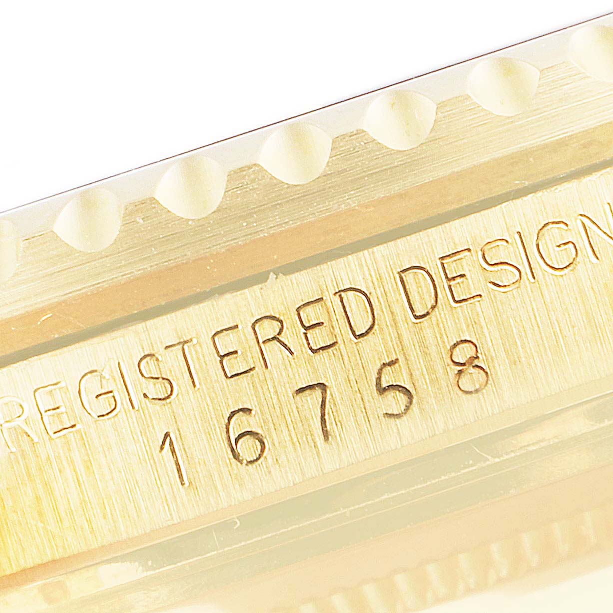 This image shows a close-up of the serial number and design text on a bezel edge of a Vintage Collection Rolex model 16758.