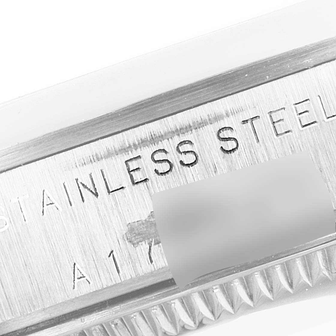 The image shows a close-up of the casing edge of a mid-size Rolex watch, featuring engraved text "STAINLESS STEEL."