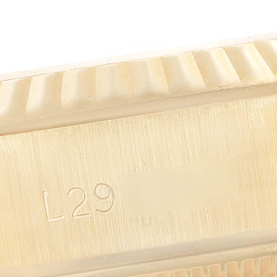 The image shows a close-up of the side of a Rolex President 69178 Women's Yellow Gold Champagne Dial 69178 Women's Yellow Gold Champagne Dial model watch, displaying its fluted bezel and part of the engraved serial number.