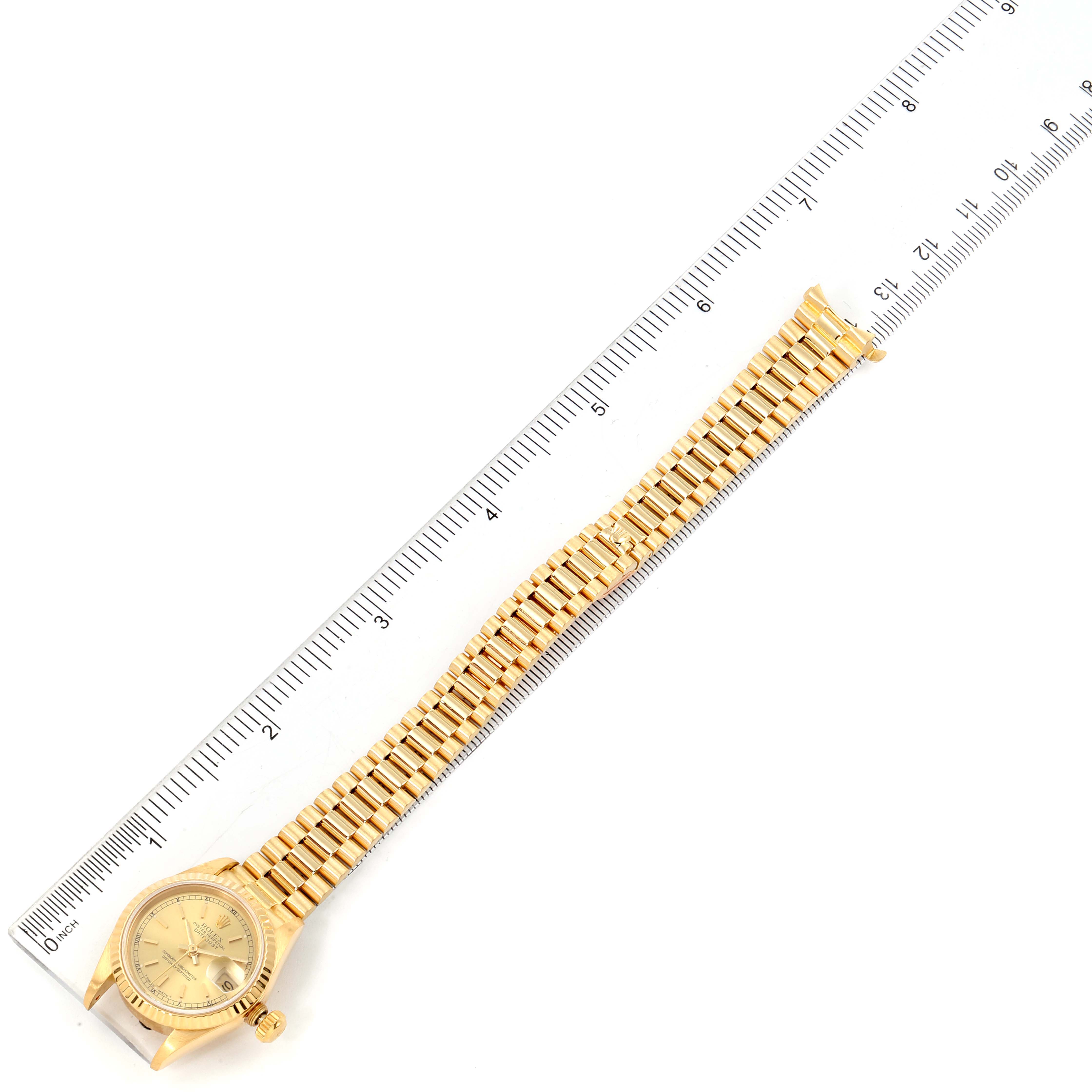 This image shows a fully extended Rolex President 69178 Women's Yellow Gold Champagne Dial 69178 Women's Yellow Gold Champagne Dial model watch lying next to a ruler, displaying the face and bracelet.