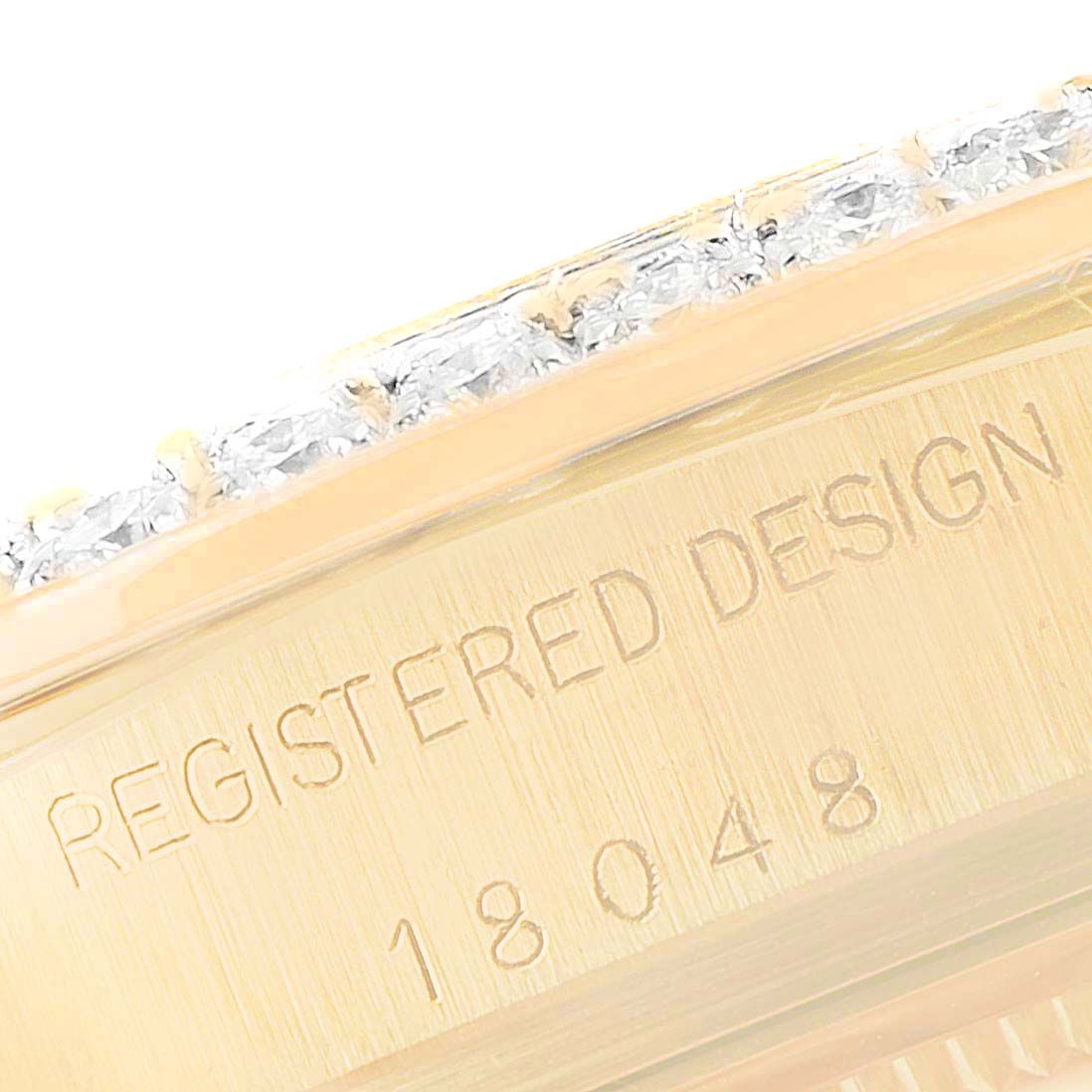The image shows a close-up of the side of a Rolex President 18048 Men
s Yellow Gold Champagne Dial 18048 Men
s Yellow Gold Champagne Dial watch, focusing on the serial number and part of the diamond-encrusted bezel.