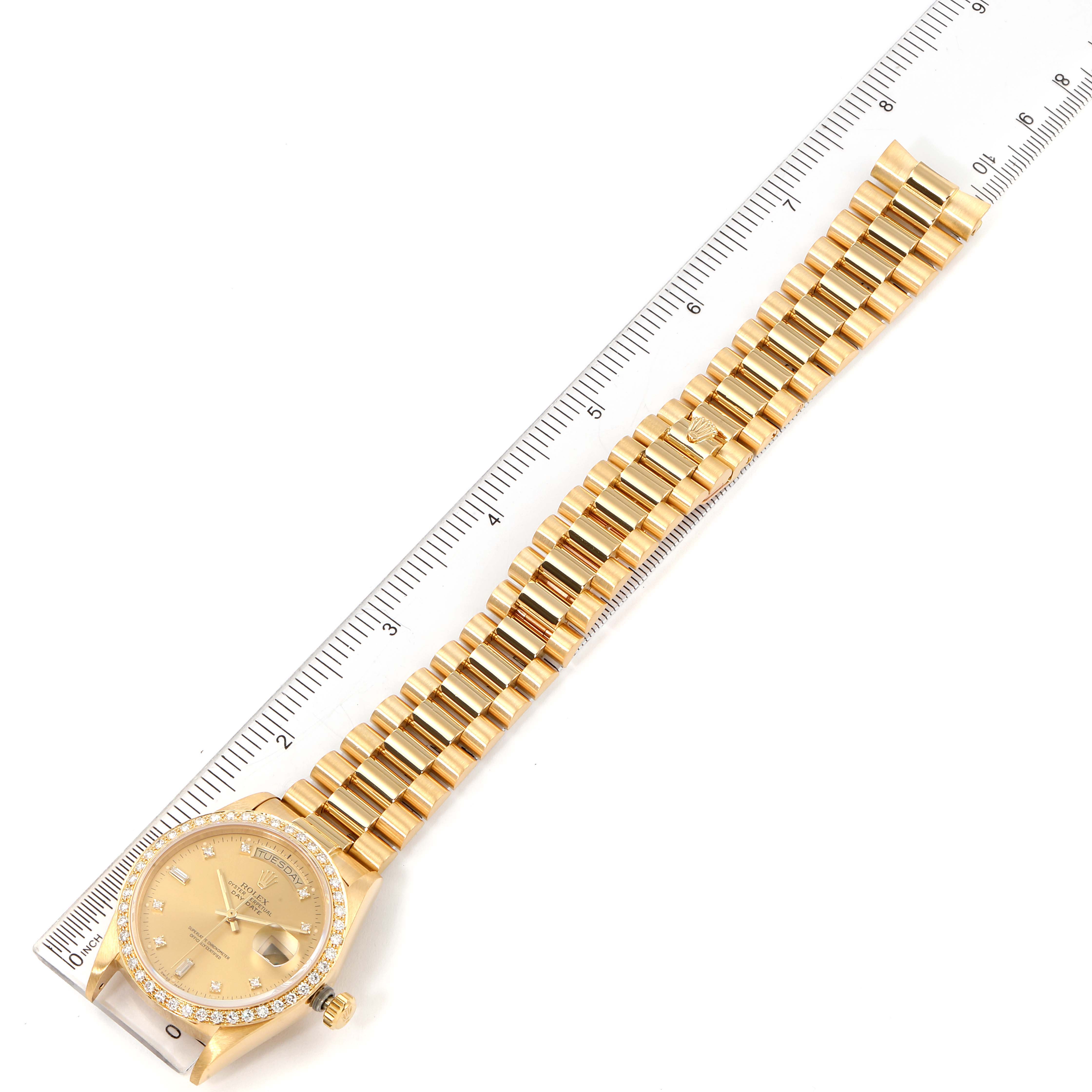 The image shows a top-down view of a Rolex President 18048 Men
s Yellow Gold Champagne Dial 18048 Men
s Yellow Gold Champagne Dial model watch, including its face and gold bracelet, aligned with a ruler.