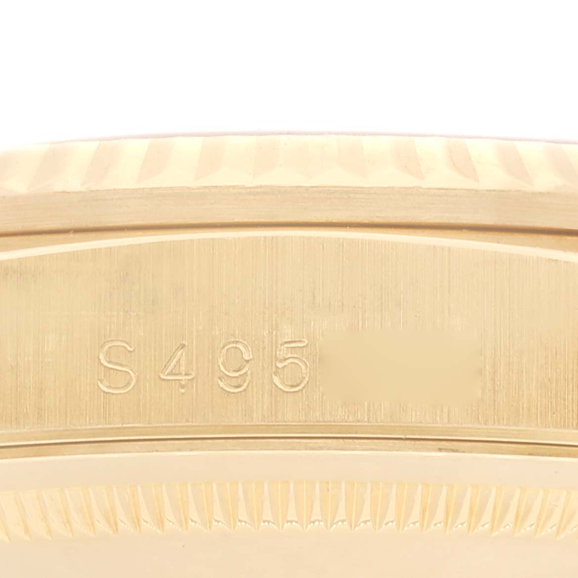 The image shows a close-up of the side of a Rolex President 18338 Men
s Yellow Gold Champagne Dial 18338 Men
s Yellow Gold Champagne Dial model watch, highlighting its engraved serial number and fluted bezel.