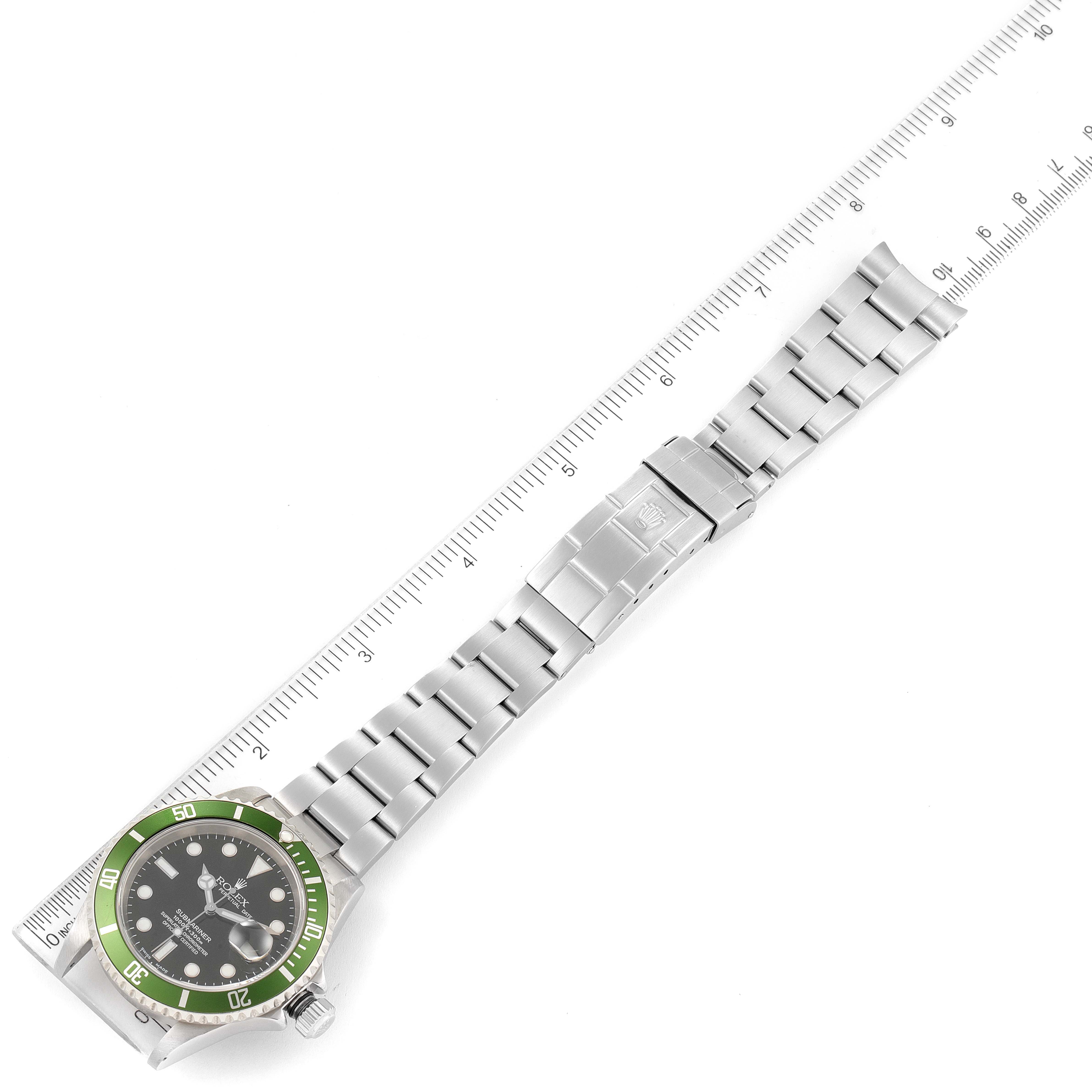 The image shows a Rolex Submariner 16610LV Men's Stainless Steel Black Dial 16610LV Men's Stainless Steel Black Dial watch laid flat with a green bezel, face, and steel bracelet, and measured against a ruler.