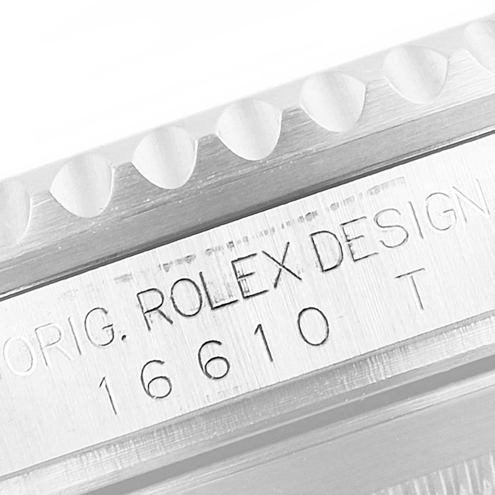 The image shows a close-up of the Rolex design and model number "16610 T" engraved on the Submariner watch case.