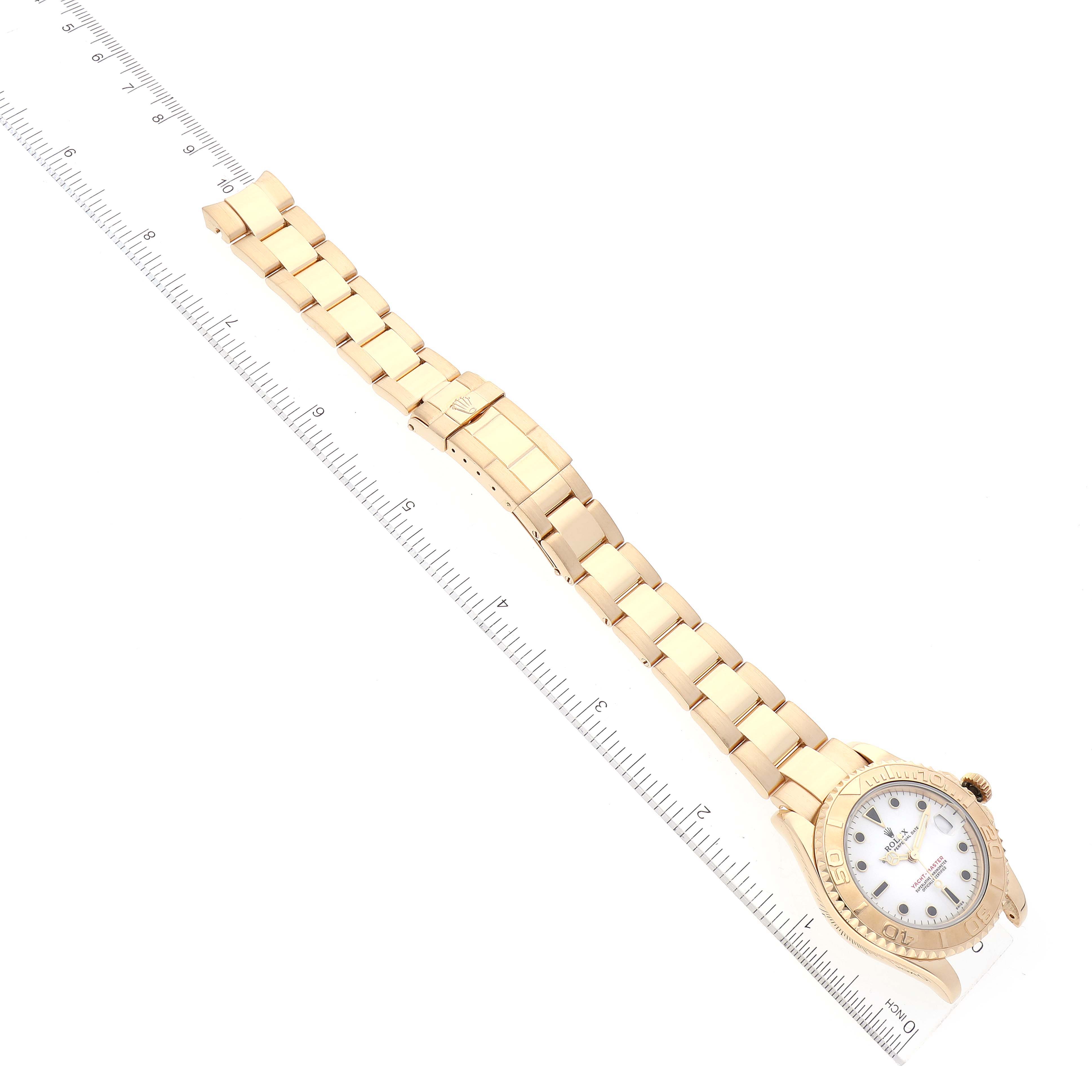 The image shows a Rolex Yacht-Master 68628 Men's Yellow Gold White Dial 68628 Men's Yellow Gold White Dial watch laid flat with its full bracelet and clasp visible alongside a measuring ruler.