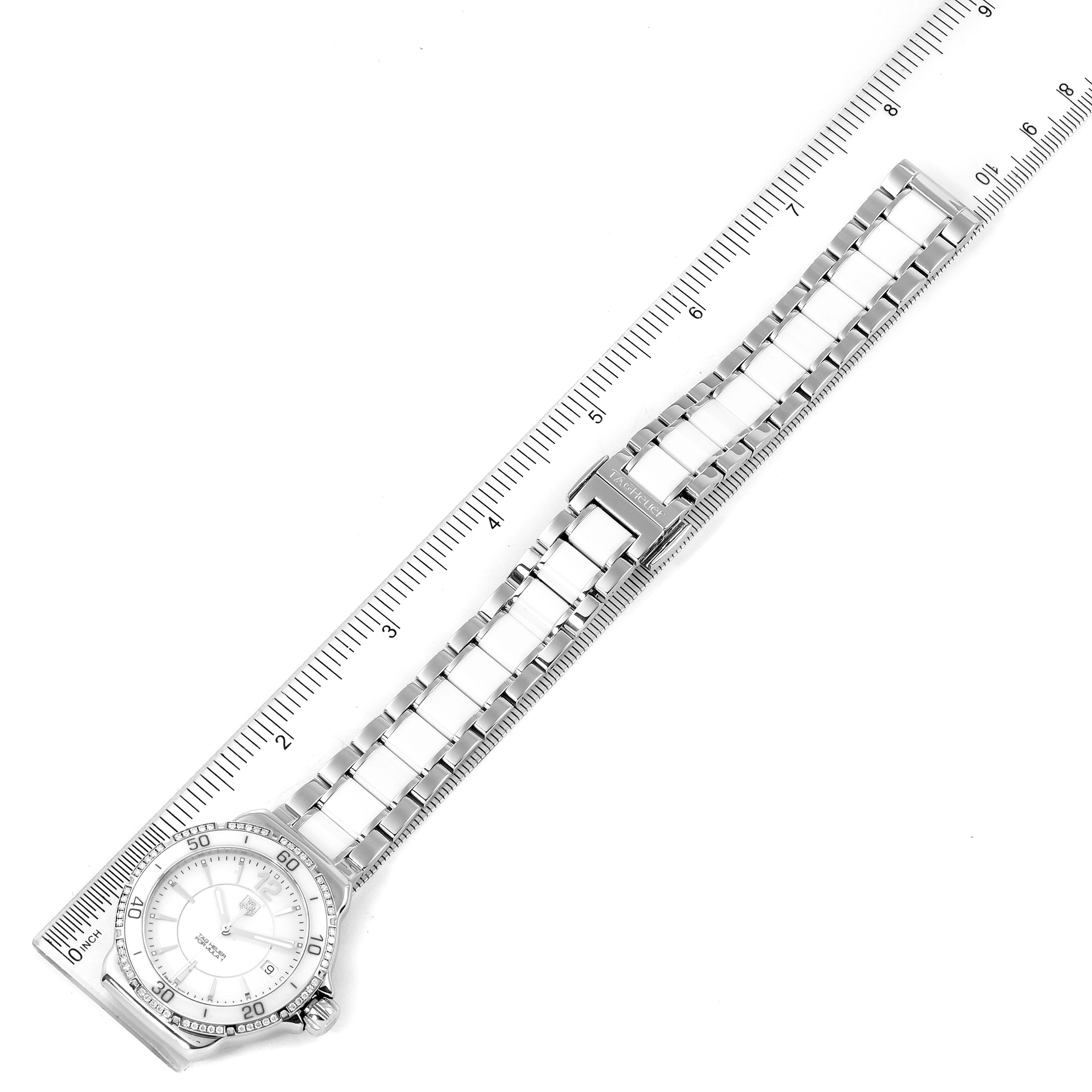 Aerial view of a Tag Heuer Formula 1 WAH1213.BA0861 Women's Stainless Steel White Dial WAH1213.BA0861 Women's Stainless Steel White Dial watch featuring its dial, bezel, metal bracelet, and a ruler for scale.