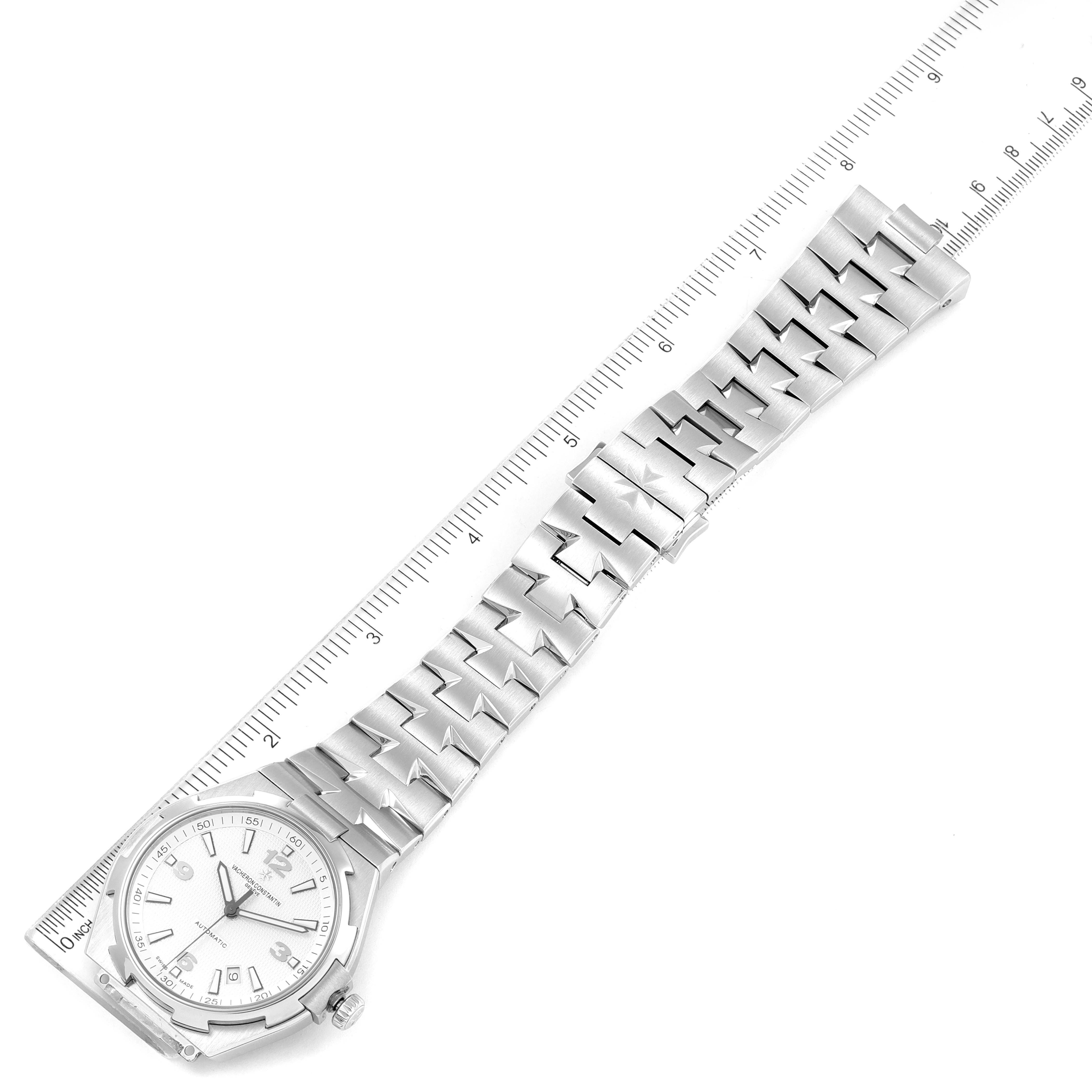 The image shows a top-down view of the Vacheron Constantin Overseas 47040B01A-9093 Men's Stainless Steel Silver Dial 47040B01A-9093 Men's Stainless Steel Silver Dial model watch with its silver bracelet alongside a ruler.