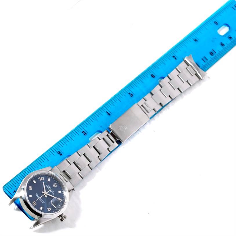 The Rolex Date 15200 Men's Stainless Steel Blue Dial 15200 Men's Stainless Steel Blue Dial model watch is shown from a top view, displaying the face, band, and clasp against a blue ruler.