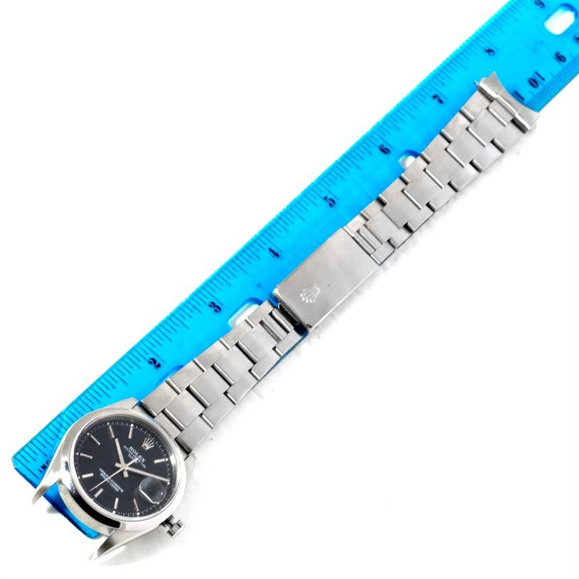 The image shows a Rolex Date 15200 Men's Stainless Steel Black Dial 15200 Men's Stainless Steel Black Dial model watch laid flat next to a blue ruler, displaying the face, bracelet, and clasp.