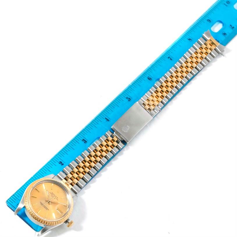 This image shows the Rolex Date 15053 Men's Steel and Gold (two tone) Champagne Dial 15053 Men's Steel and Gold (two tone) Champagne Dial watch model placed next to a blue ruler, displaying its face and band.