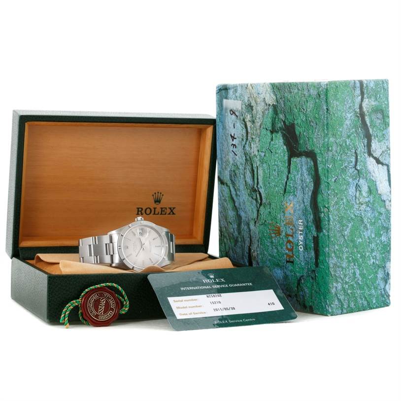 The image shows a Rolex Date 15210 Men's Stainless Steel Silver Dial 15210 Men's Stainless Steel Silver Dial watch in its box, accompanied by a guarantee card, hang tags, and a watch manual.