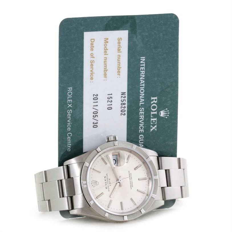 The image shows a Rolex Date 15210 Men's Stainless Steel Silver Dial 15210 Men's Stainless Steel Silver Dial model watch with its bracelet fully displayed, positioned in front of its service card.