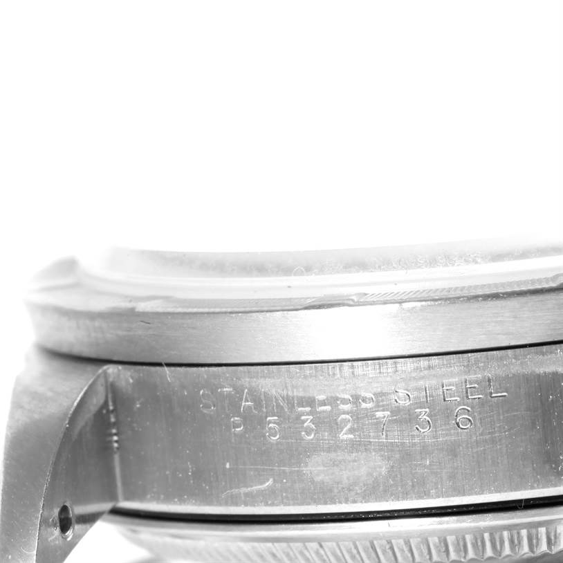 The image shows a close-up side view of the case and bezel of a Rolex Date 15210 Men's Stainless Steel White Dial 15210 Men's Stainless Steel White Dial model watch, with "Stainless Steel" and a serial number engraved.