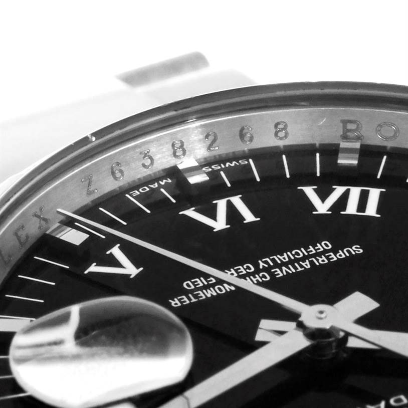 The image shows a close-up of the dial and bezel of a Rolex Date 115200 Men's Stainless Steel Black Dial 115200 Men's Stainless Steel Black Dial model, capturing part of the Roman numerals and serial number.